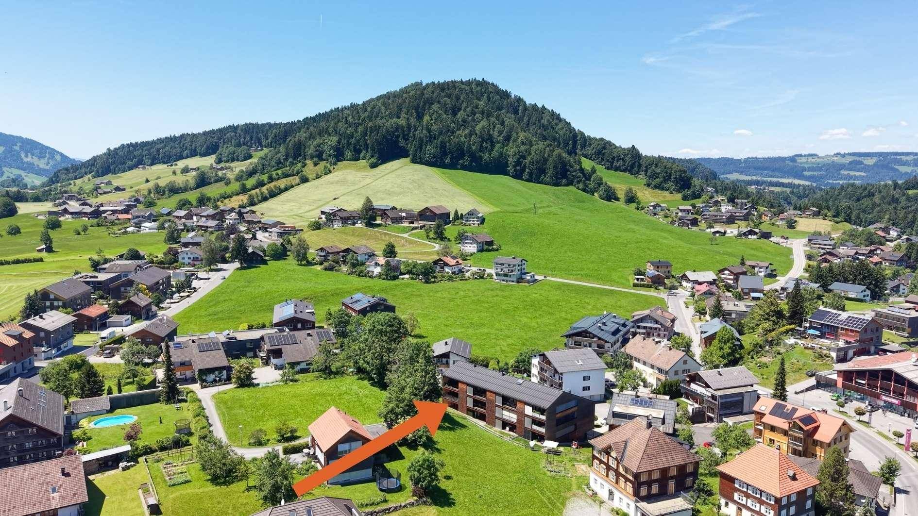 Luftaufnahme einer ländlichen Wohngegend mit grünen Hügeln und Häusern.