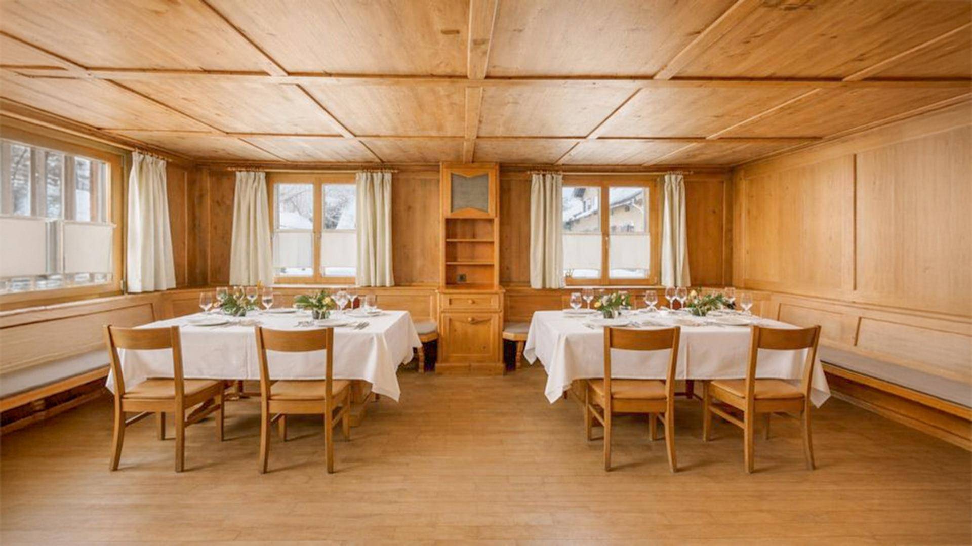 Traditioneller Speisesaal mit Holztäfelung, Holzboden und zwei gedeckten Tischen für Gäste.
