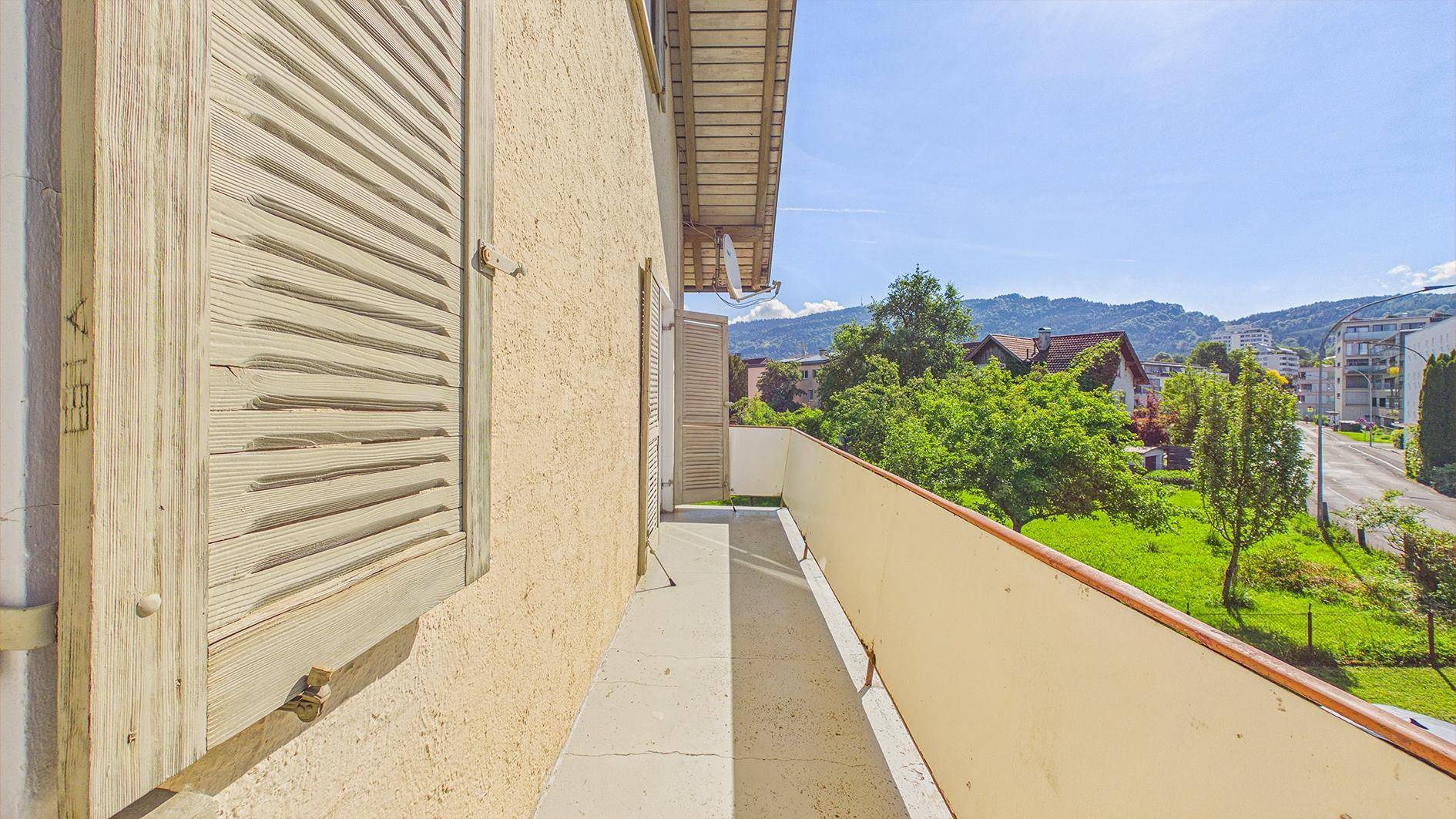 Schmaler Balkon mit Holzläden und Blick auf die Umgebung, ideal für frische Luft.