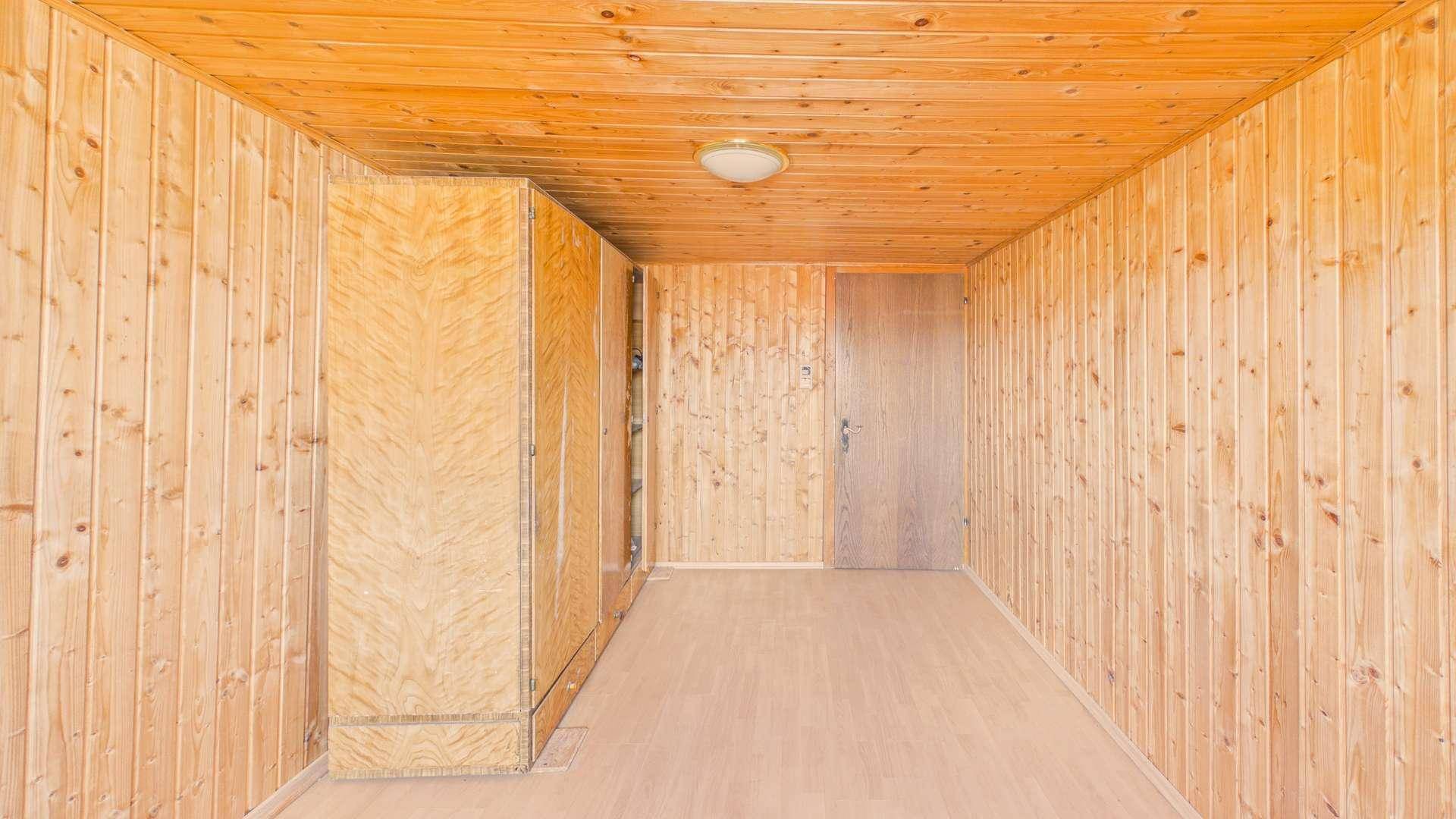 Geräumiges Zimmer mit Holzverkleidung, Holzboden und einem großen Kleiderschrank.