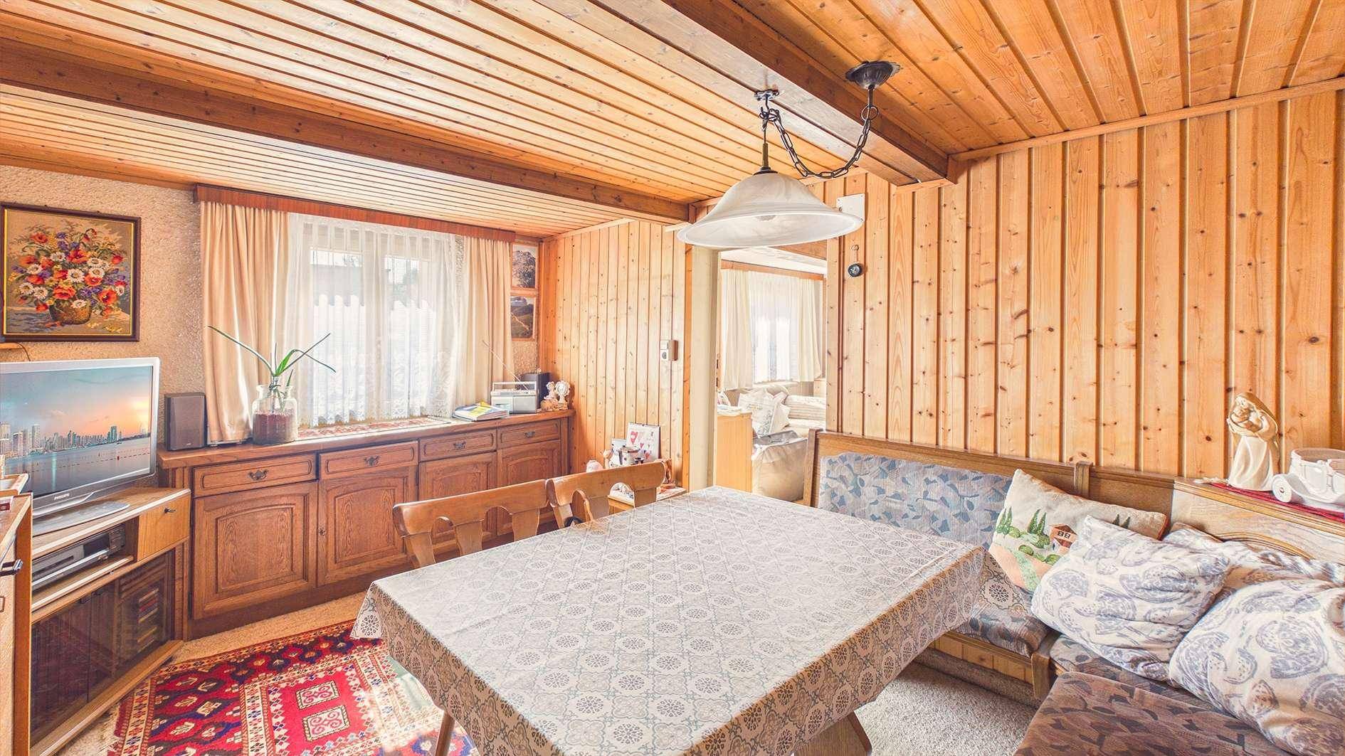 Rustikaler Wohn- und Essbereich mit Holzvertäfelung an Wänden und Decke.