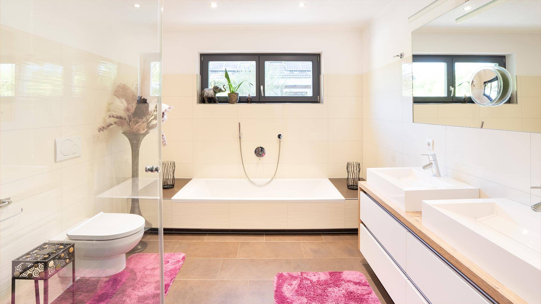 Modernes Badezimmer mit Doppelwaschbecken, Badewanne, Dusche und Fenster für Tageslicht.