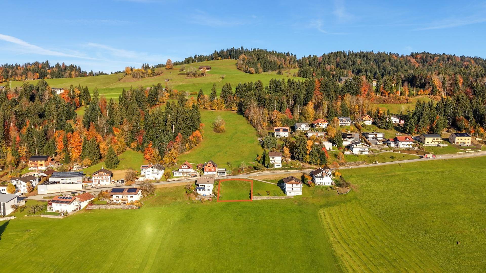 Luftaufnahme einer ländlichen Siedlung mit Häusern, Wiesen und Wäldern, inklusive eines markierten Grundstücks.