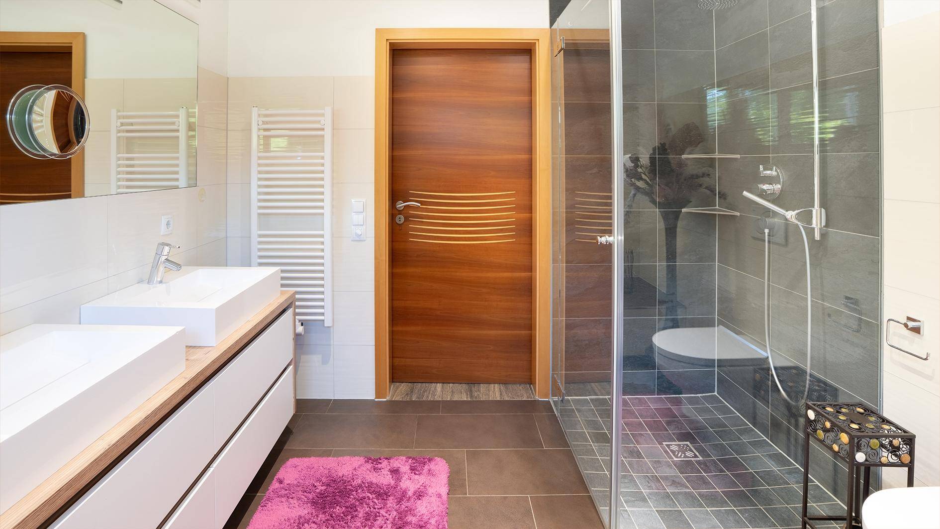 Modernes Badezimmer mit Doppelwaschbecken, begehbarer Dusche und beheiztem Handtuchhalter.