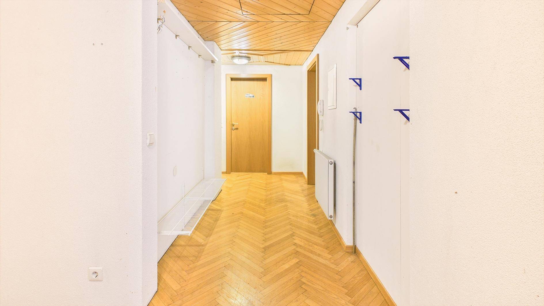 Gemütlicher Flur mit Fischgrätparkett, Holzdecke und Garderobenhaken an der Wand.
