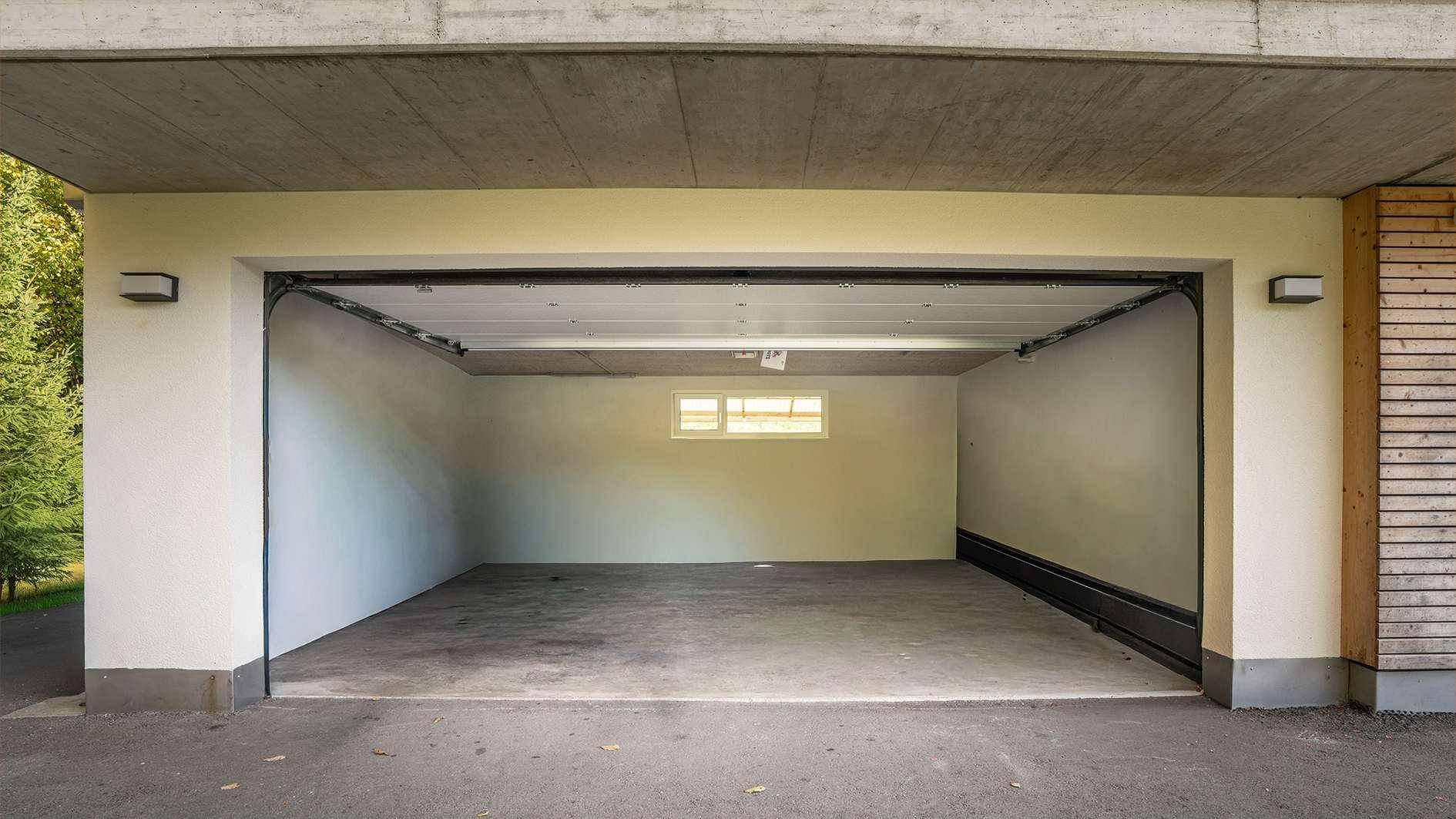 Geräumige Garage mit offenem Tor, bietet Platz für Fahrzeuge und zusätzlichen Stauraum.