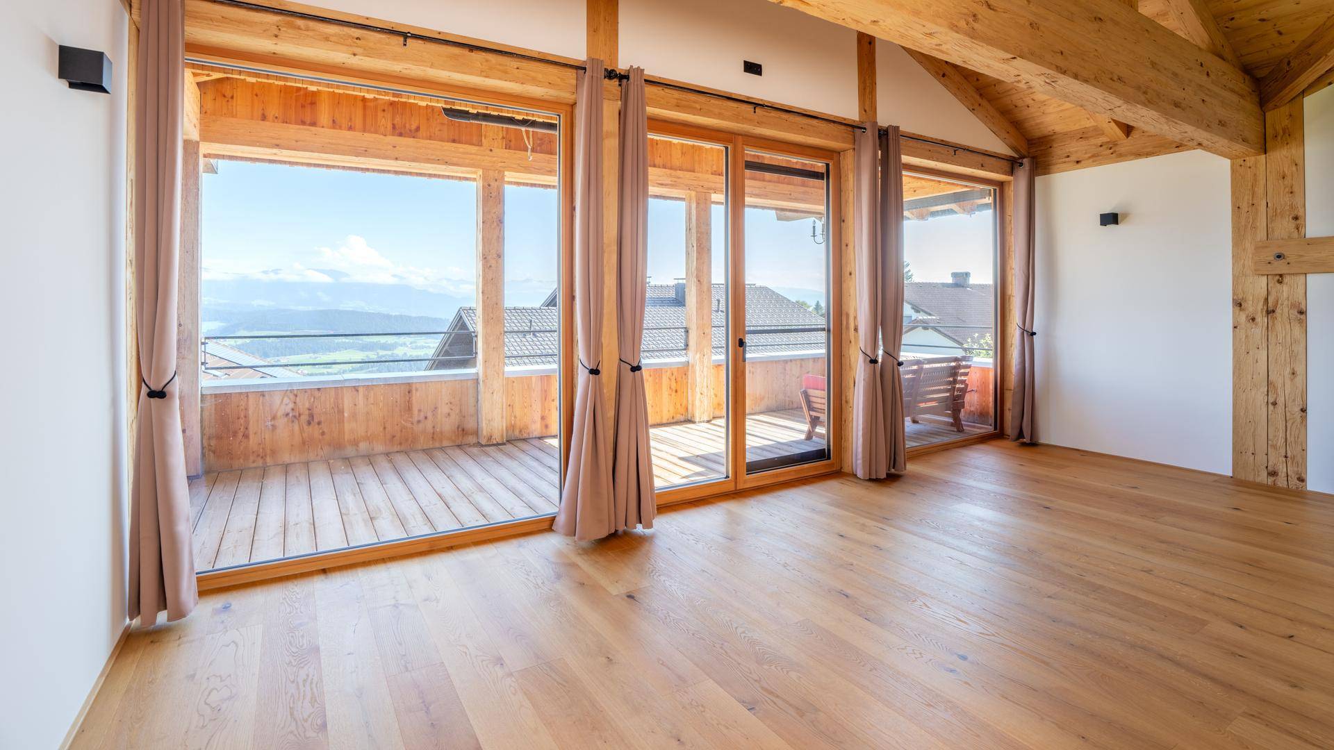 Schlafzimmer mit Zugang zum Balkon, bodentiefen Fenstern und weitem Blick auf die Berge.