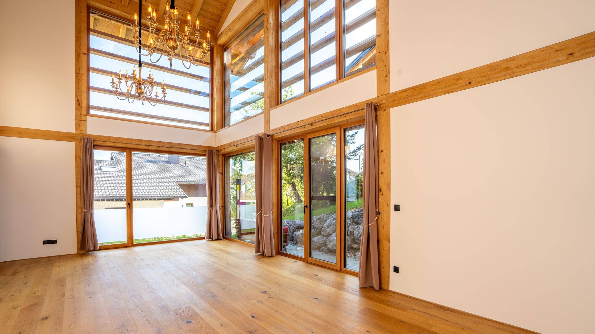 Großzügiges Wohnzimmer mit hohen Decken, Holzbalken und großen Fenstern für viel Tageslicht.