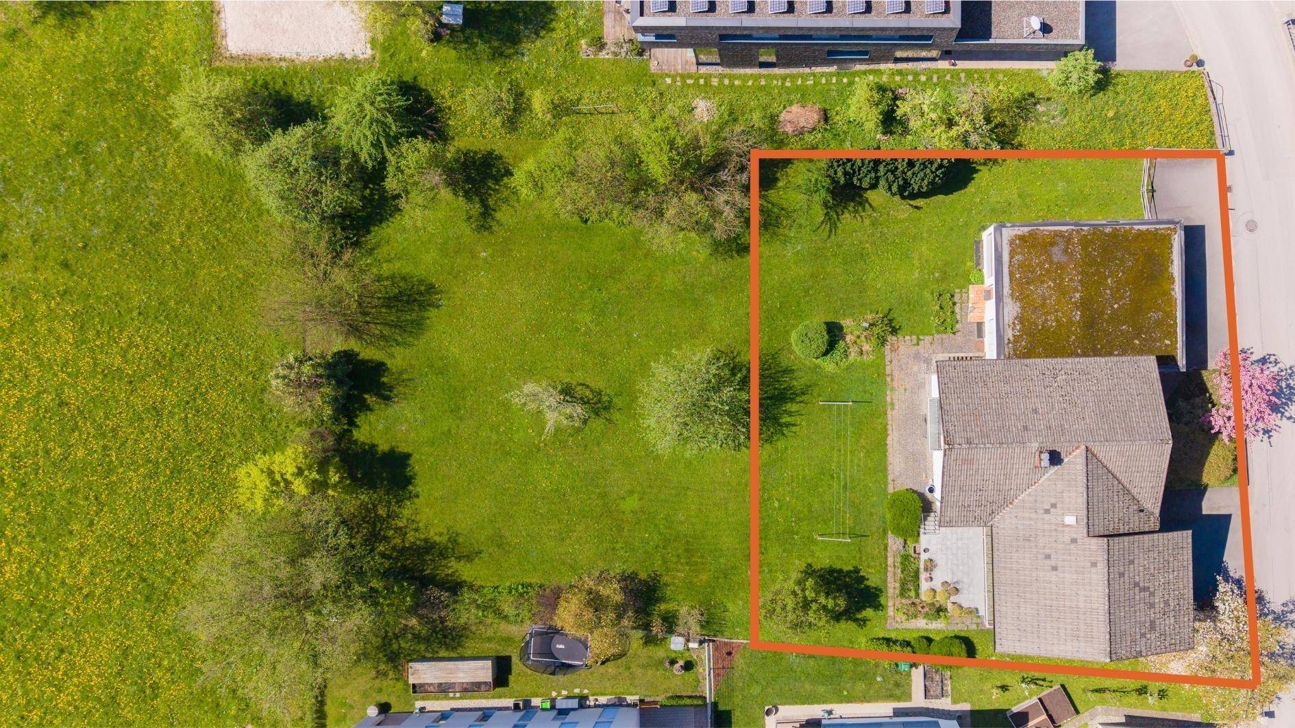Weitere Luftaufnahme des Grundstücks, die das Haus und die weitläufige Grünfläche zeigt, rot umrandet.