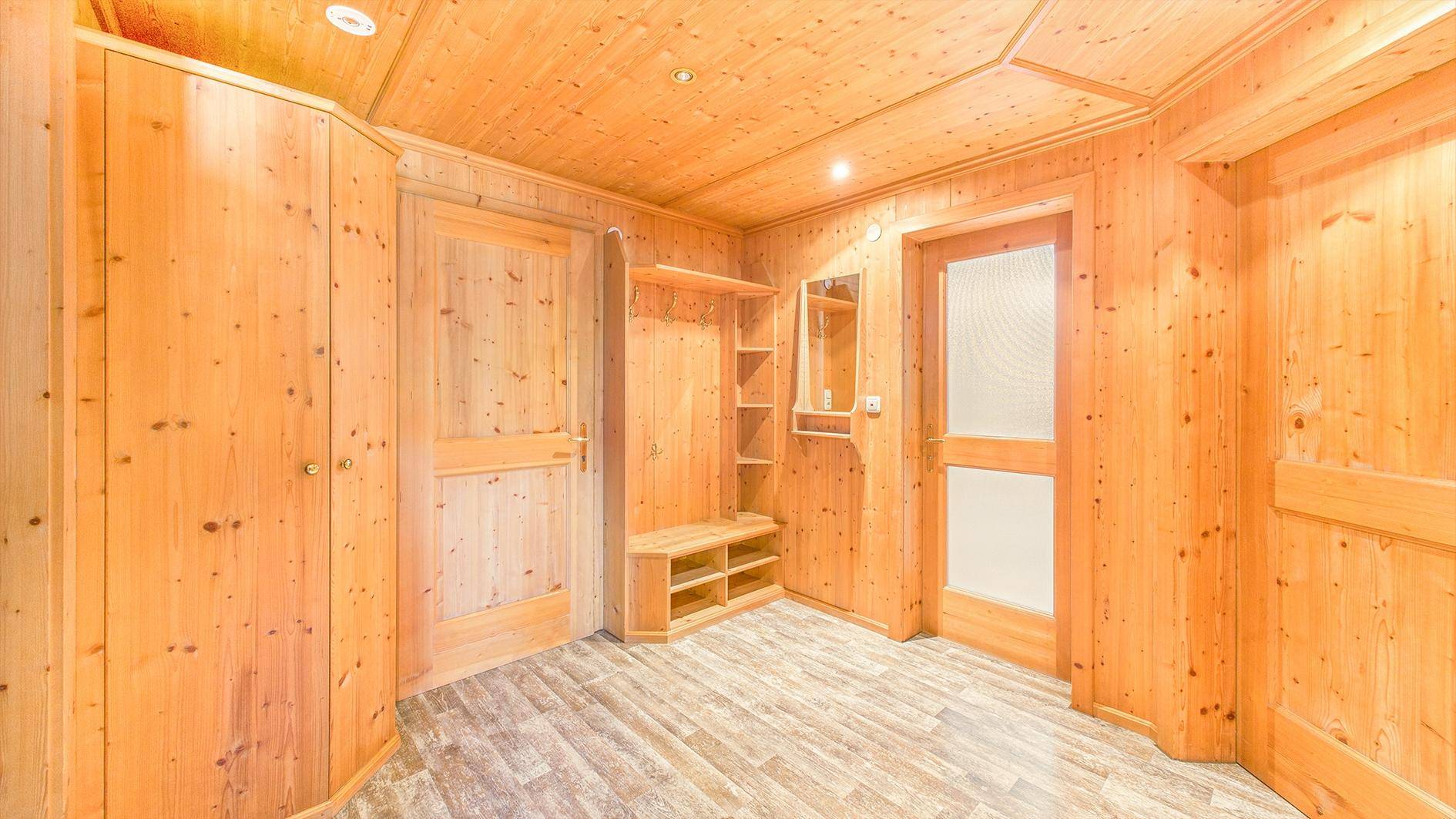Eingangsbereich mit Holztäfelung, integrierten Schränken und Ablagemöglichkeiten für Kleidung.