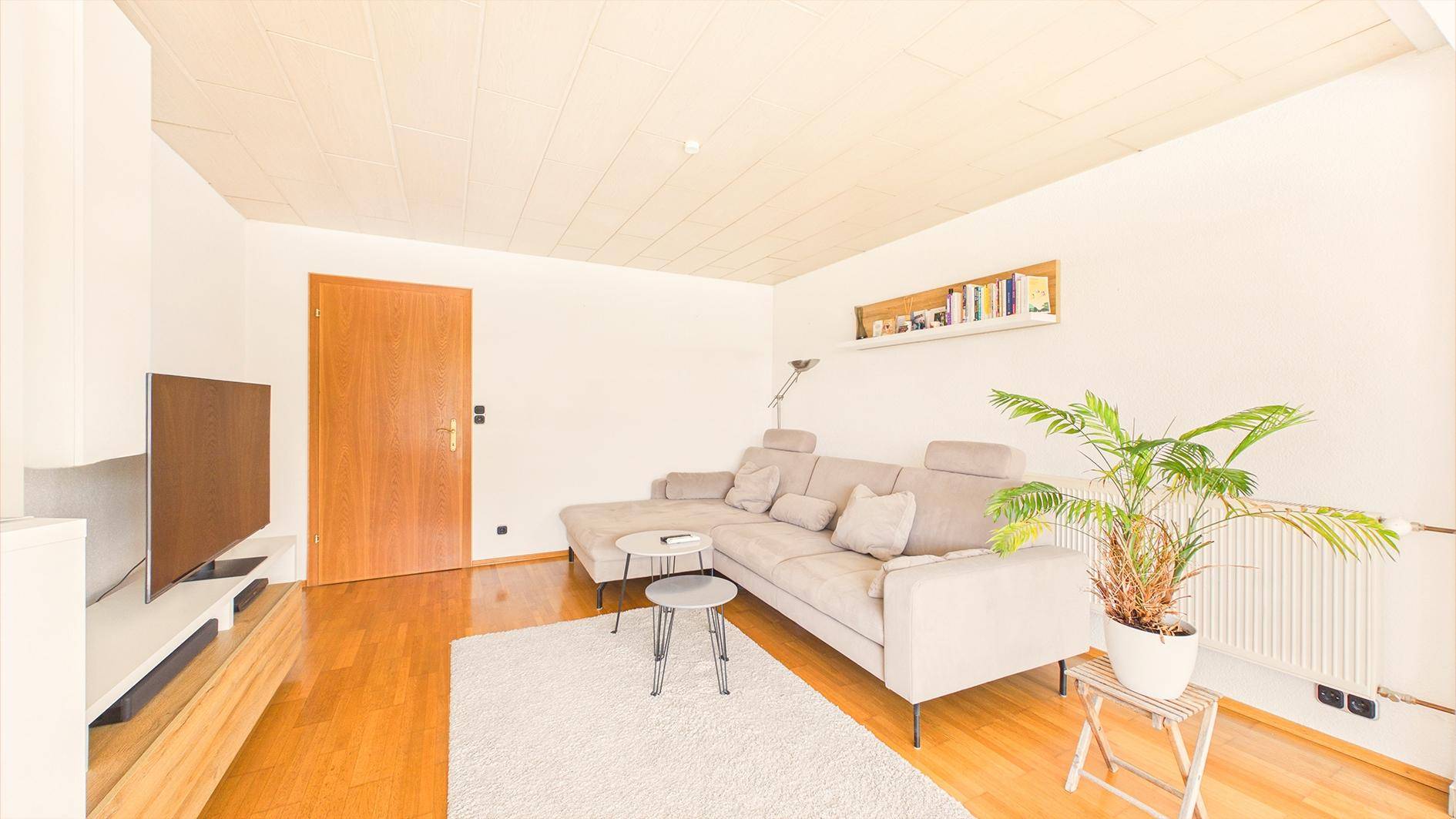 Helles Wohnzimmer mit Holzboden, bequemer Couch und schwebendem TV-Möbel.