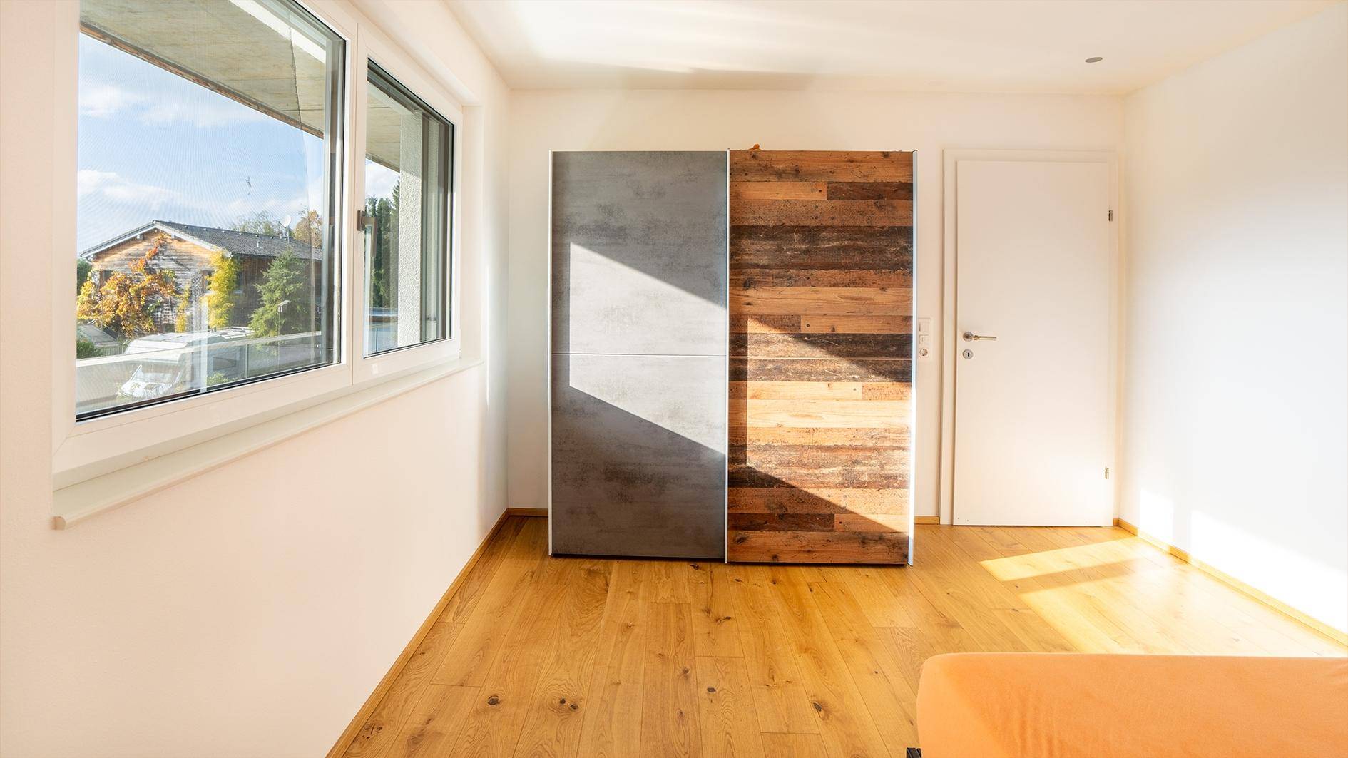 Helles Zimmer mit modernem Schiebetürenschrank und hellem Parkettboden.