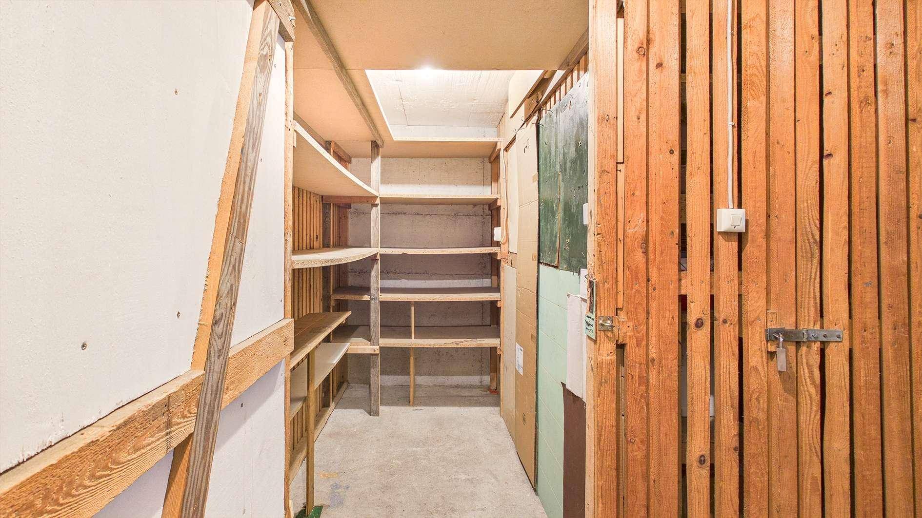 Einfacher Abstellraum mit Holzregalen und Betonboden, ideal für Lagerzwecke.
