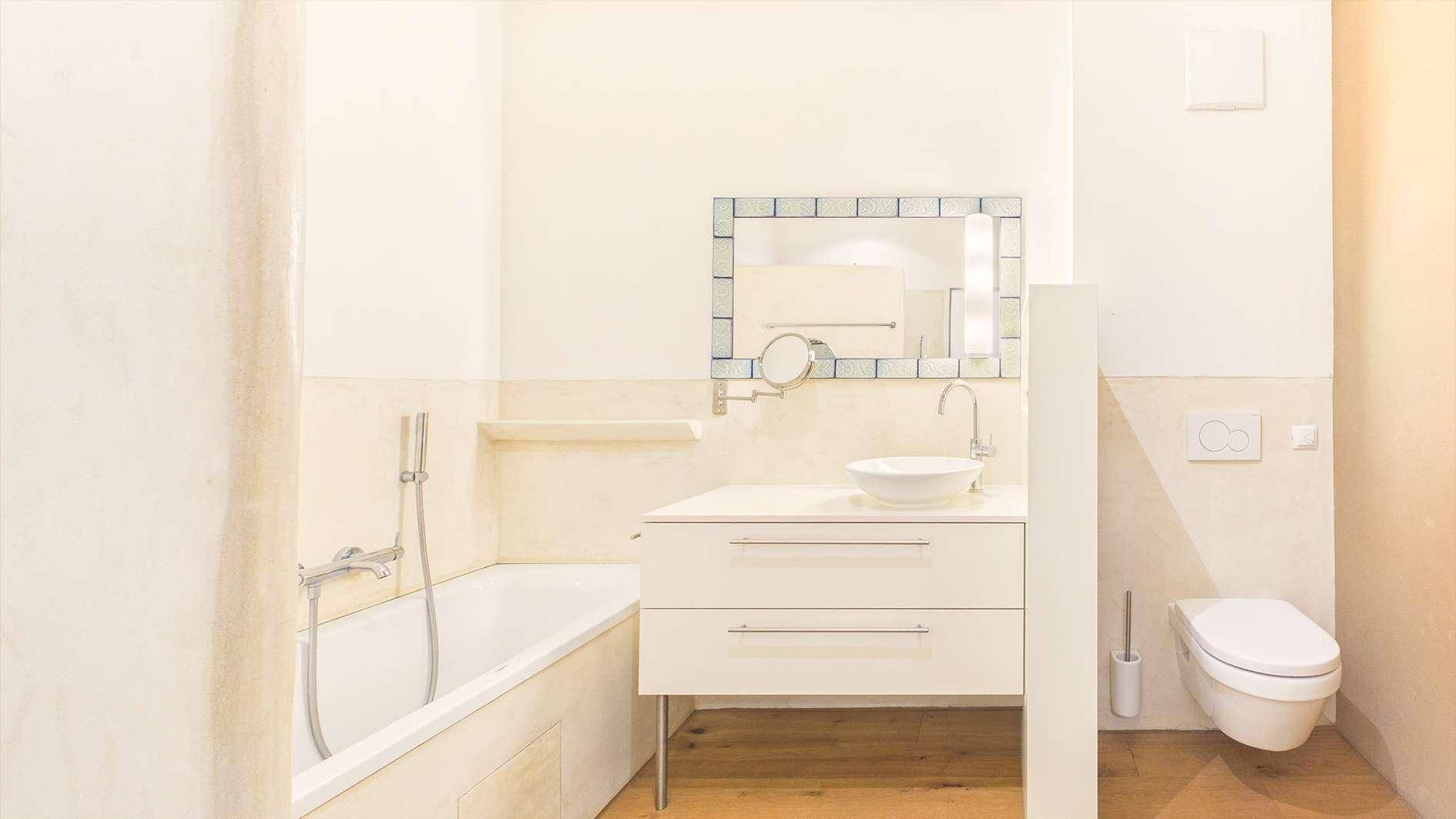 Helles Badezimmer mit Badewanne, modernem Waschbecken und Wand-WC.