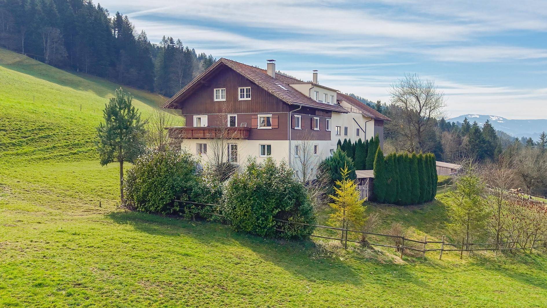 Charmantes Landhaus in idyllischer Hügellandschaft mit grünen Wiesen und Bäumen.