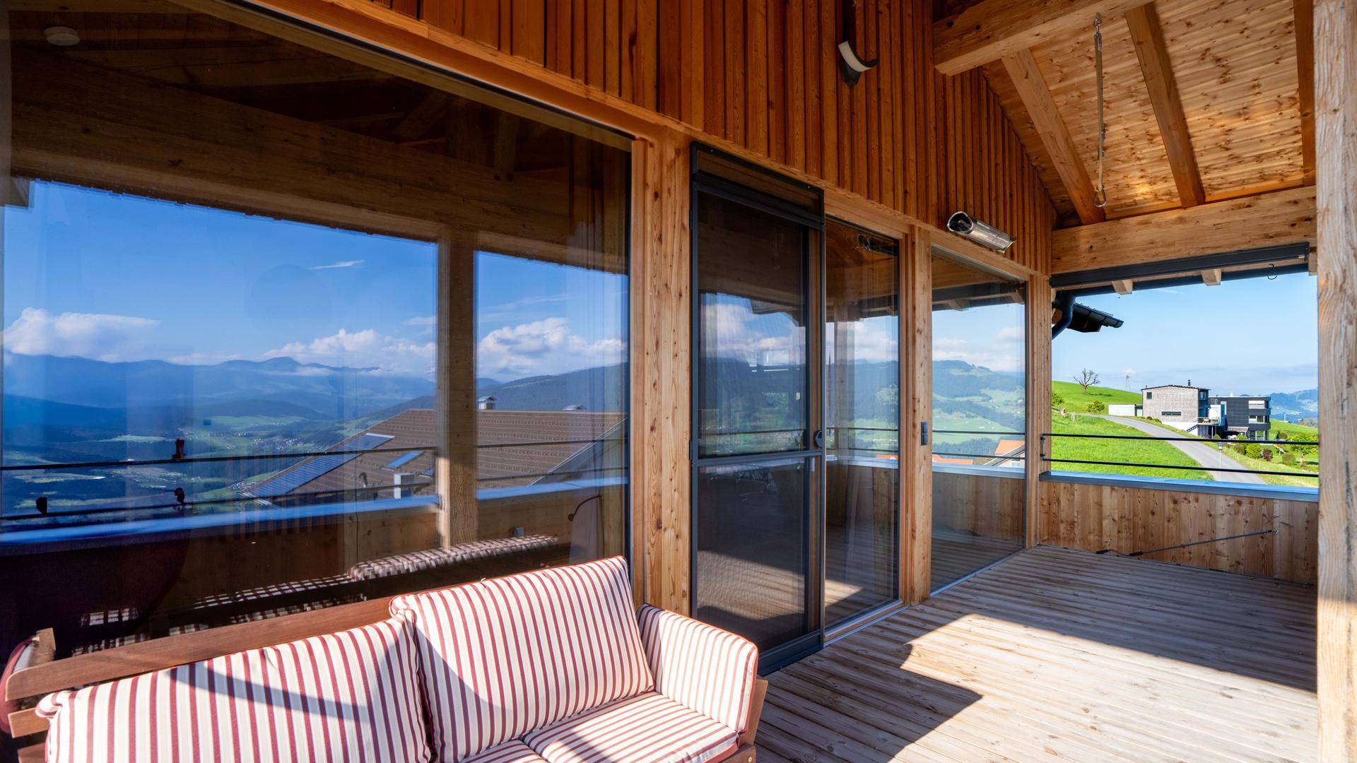 Überdachter Balkon mit Holzboden und bequemen Sitzgelegenheiten, ideal für entspannte Stunden.