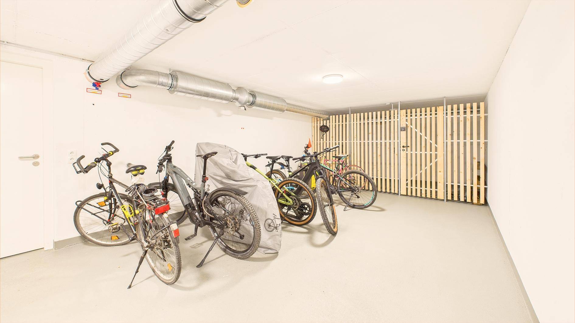 Fahrradraum mit mehreren Fahrrädern und Holzabtrennungen für Abstellbereiche.