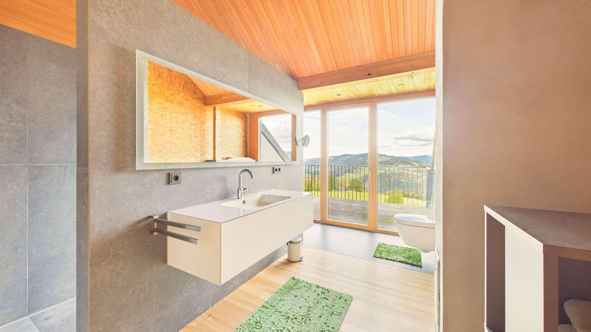 Helles Badezimmer mit Holzboden, modernen Armaturen und großem Fenster mit Bergblick.