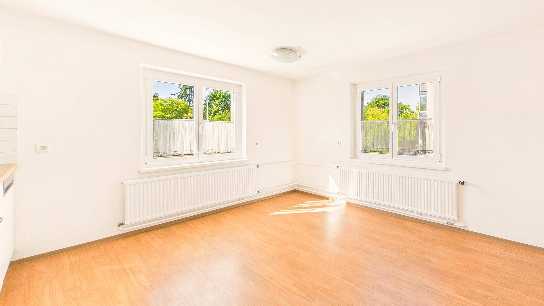 Geräumige, helle Küche mit Parkettboden und zwei Fenstern, bietet viel Tageslicht.