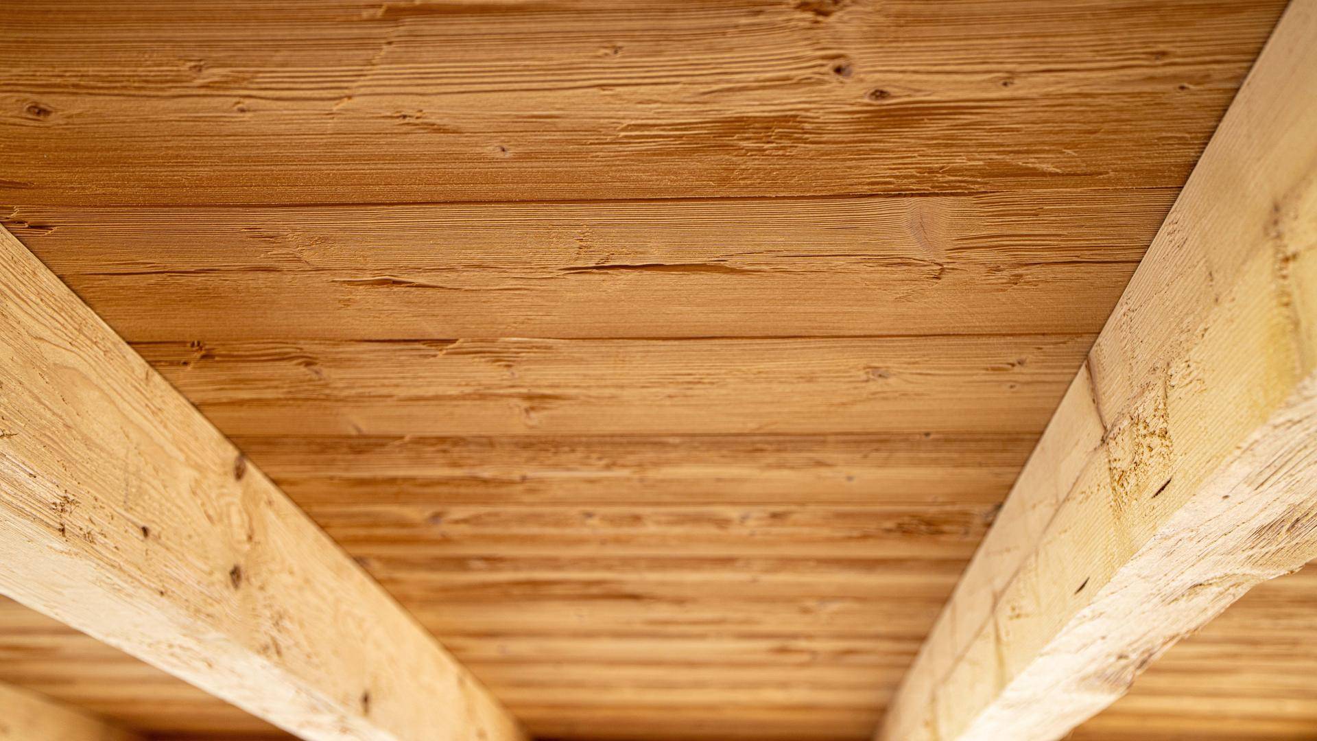Detailansicht einer Holzbalkendecke, die dem Raum eine warme und rustikale Atmosphäre verleiht.