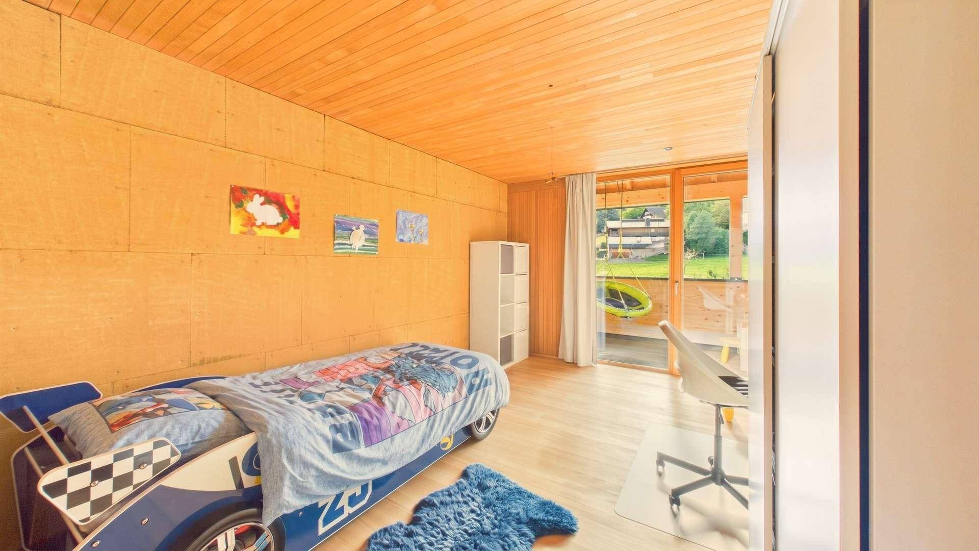 Helles Kinderzimmer mit Holzwänden, Holzboden und Zugang zum Außenbereich.