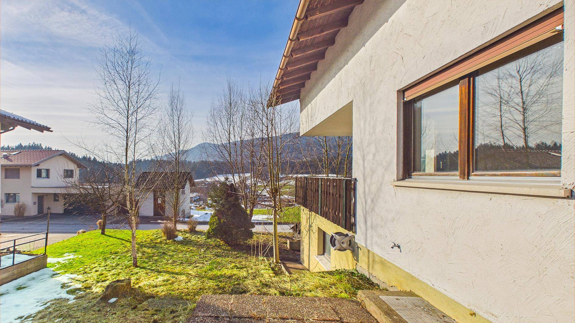 Seitenansicht des Hauses mit Balkon und Blick auf die umliegende Landschaft und Berge.