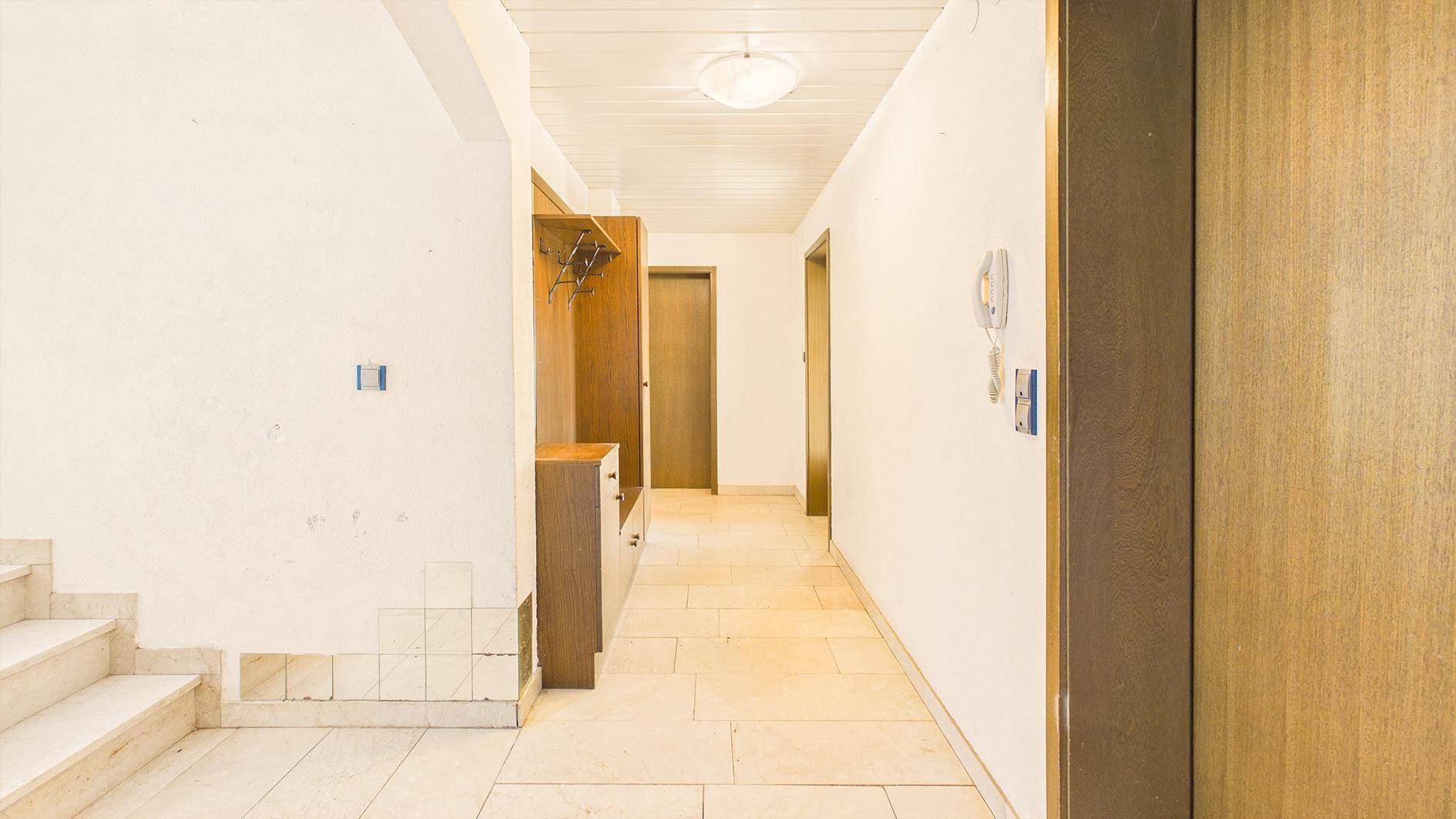 Heller Eingangsbereich mit Fliesenboden, Garderobe und Zugang zu weiteren Räumen.