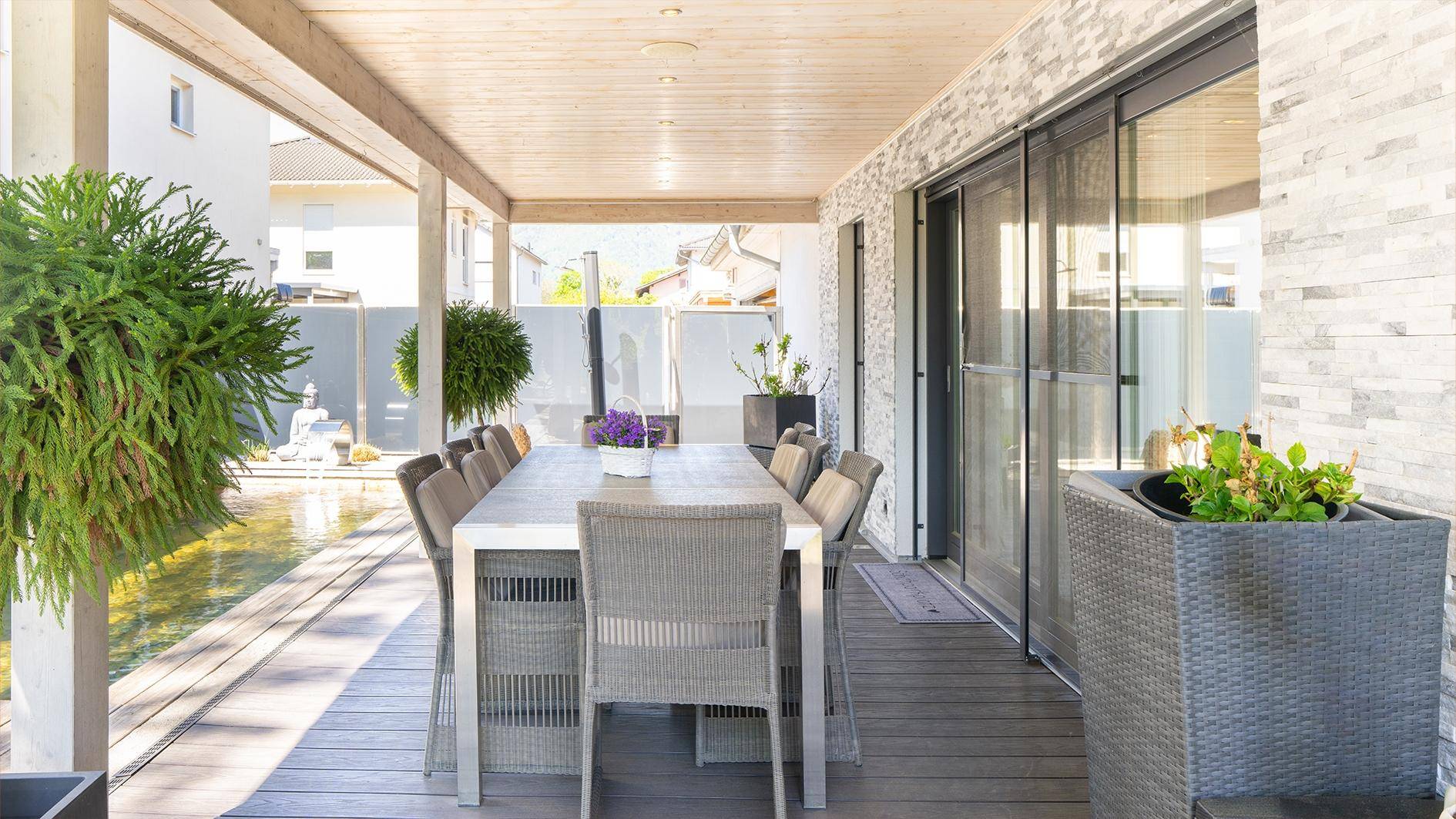 Geräumige überdachte Terrasse mit Esstisch und Schiebetüren zum Innenbereich.