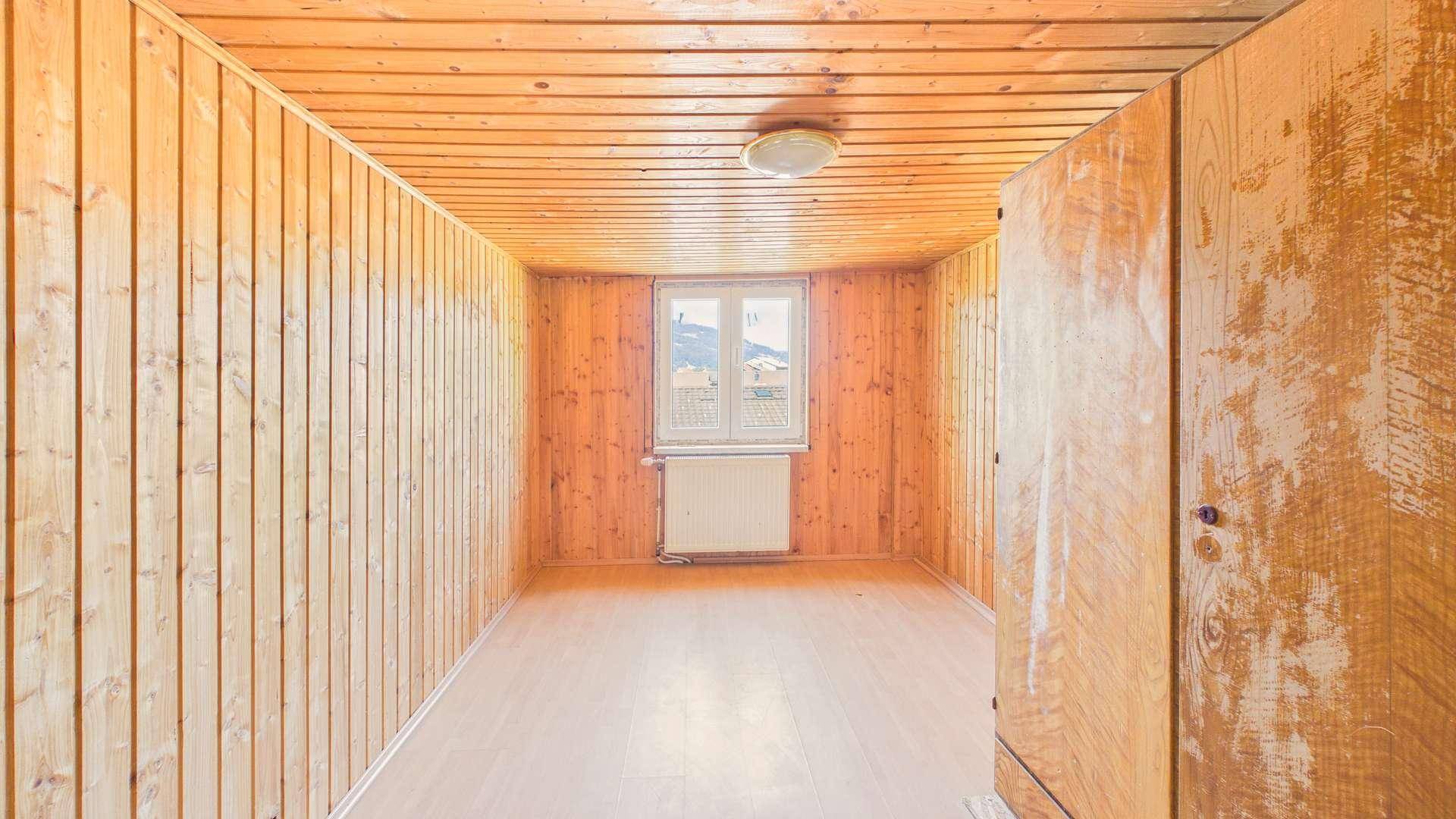 Helles Zimmer mit Holzverkleidung, Holzboden und einem Fenster mit Ausblick.