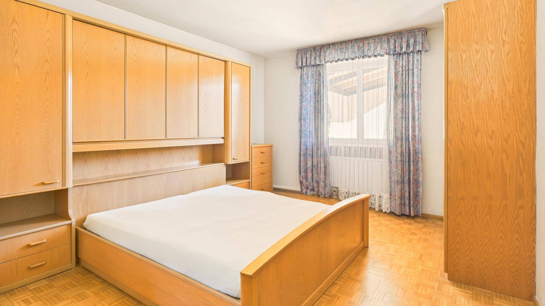 Schlafzimmer mit Einbauschränken, Doppelbett und Parkettboden.
