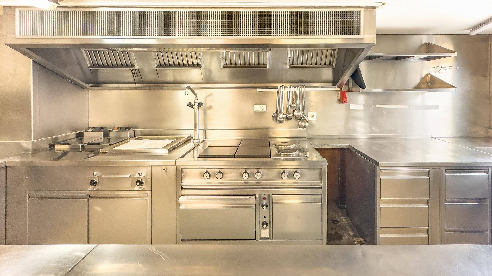Professionelle Industrieküche mit Edelstahloberflächen und Großgeräten, ideal für Gastronomie.