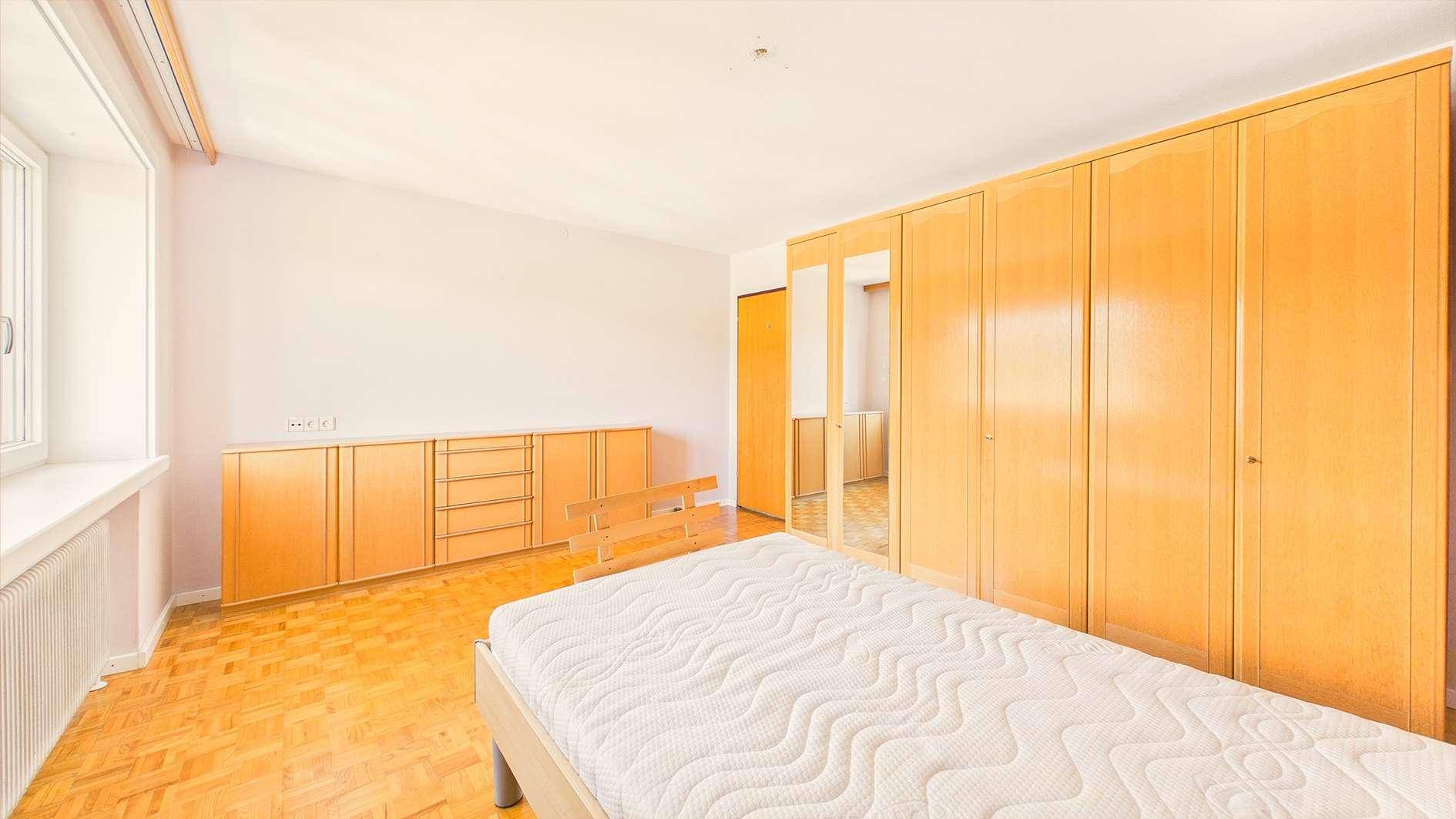 Schlafzimmer mit Holzboden, Einbauschränken und Fenster für viel Tageslicht.