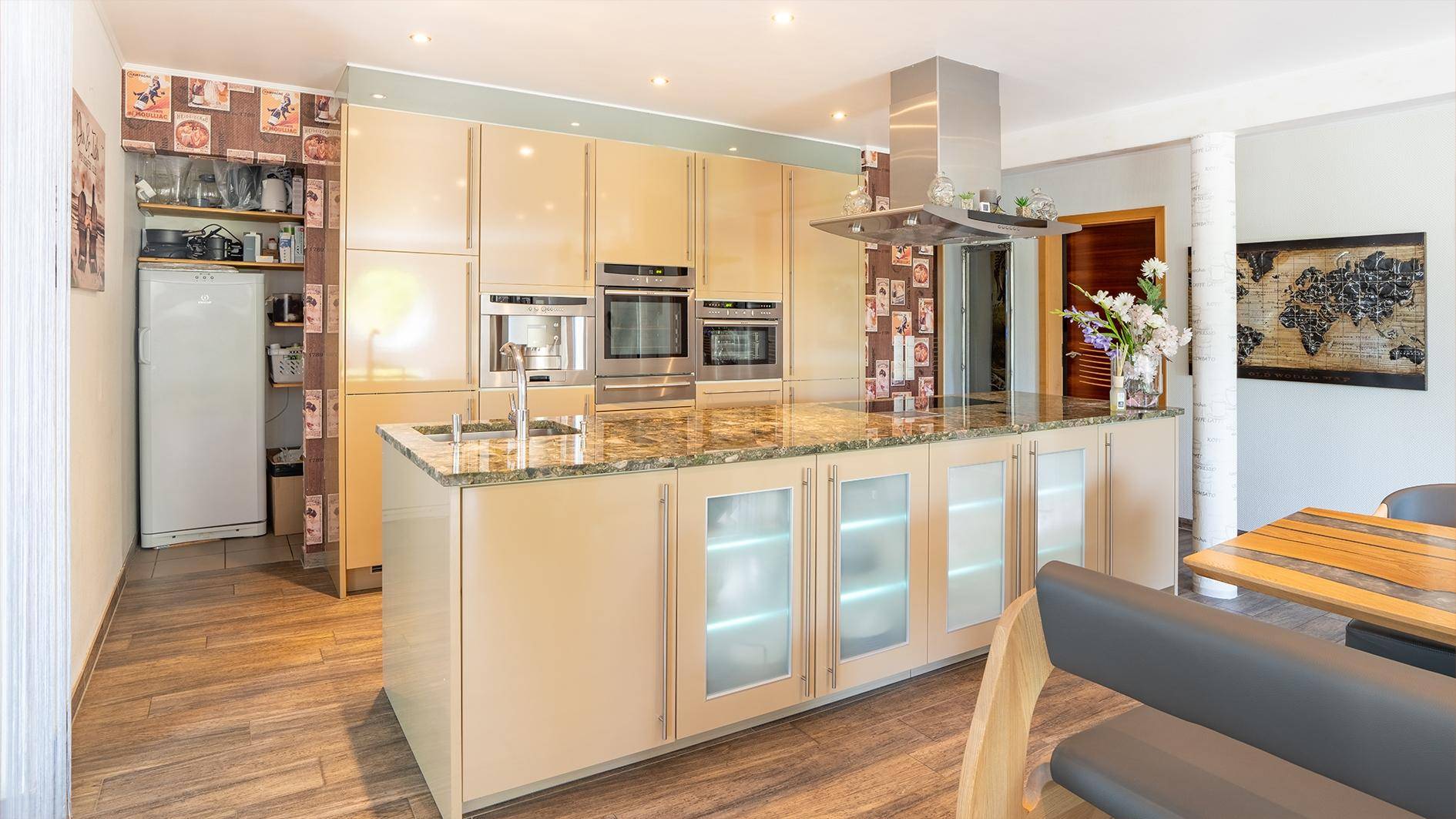 Moderne Küche mit Kücheninsel, glänzenden Fronten, integrierten Geräten und Granit-Arbeitsplatten.