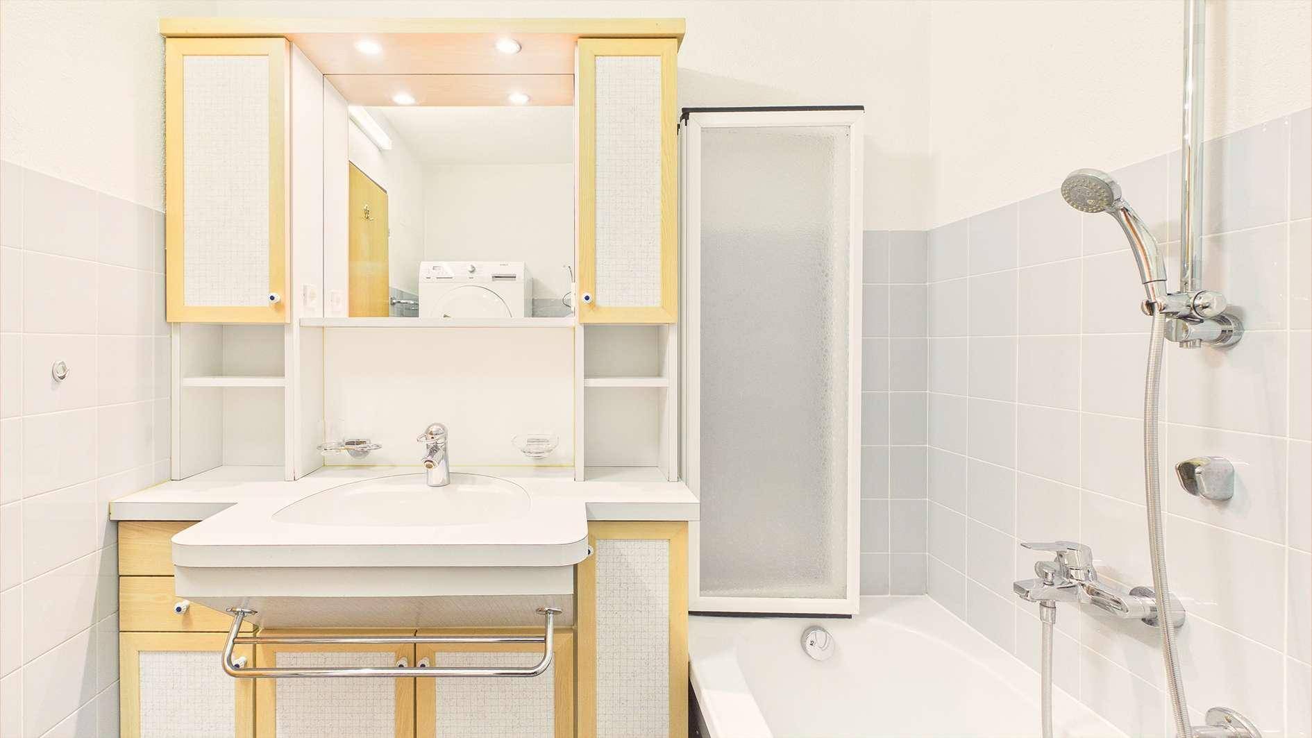 Badezimmer mit Badewanne, Duschvorrichtung und Waschtisch mit Spiegelschrank.