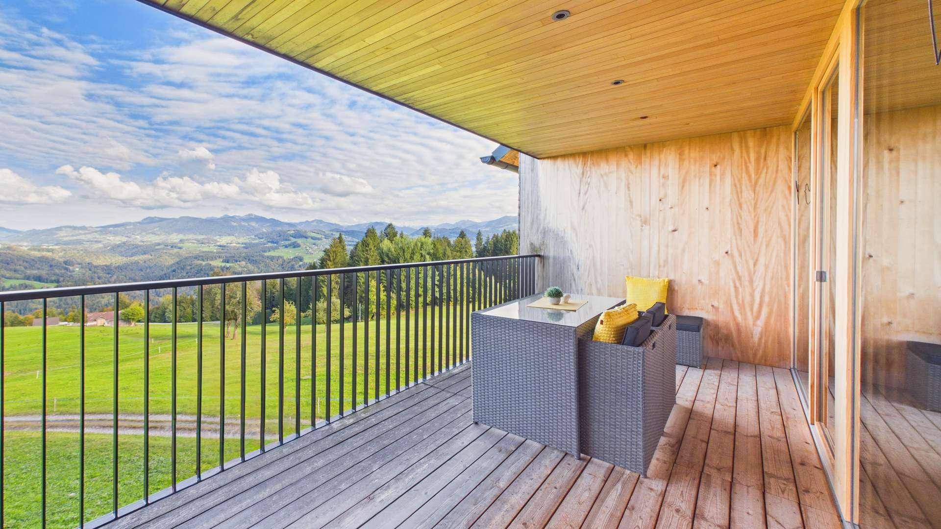Moderner Balkon mit Holzboden und Lounge-Möbeln, ideal zum Entspannen mit Bergblick.