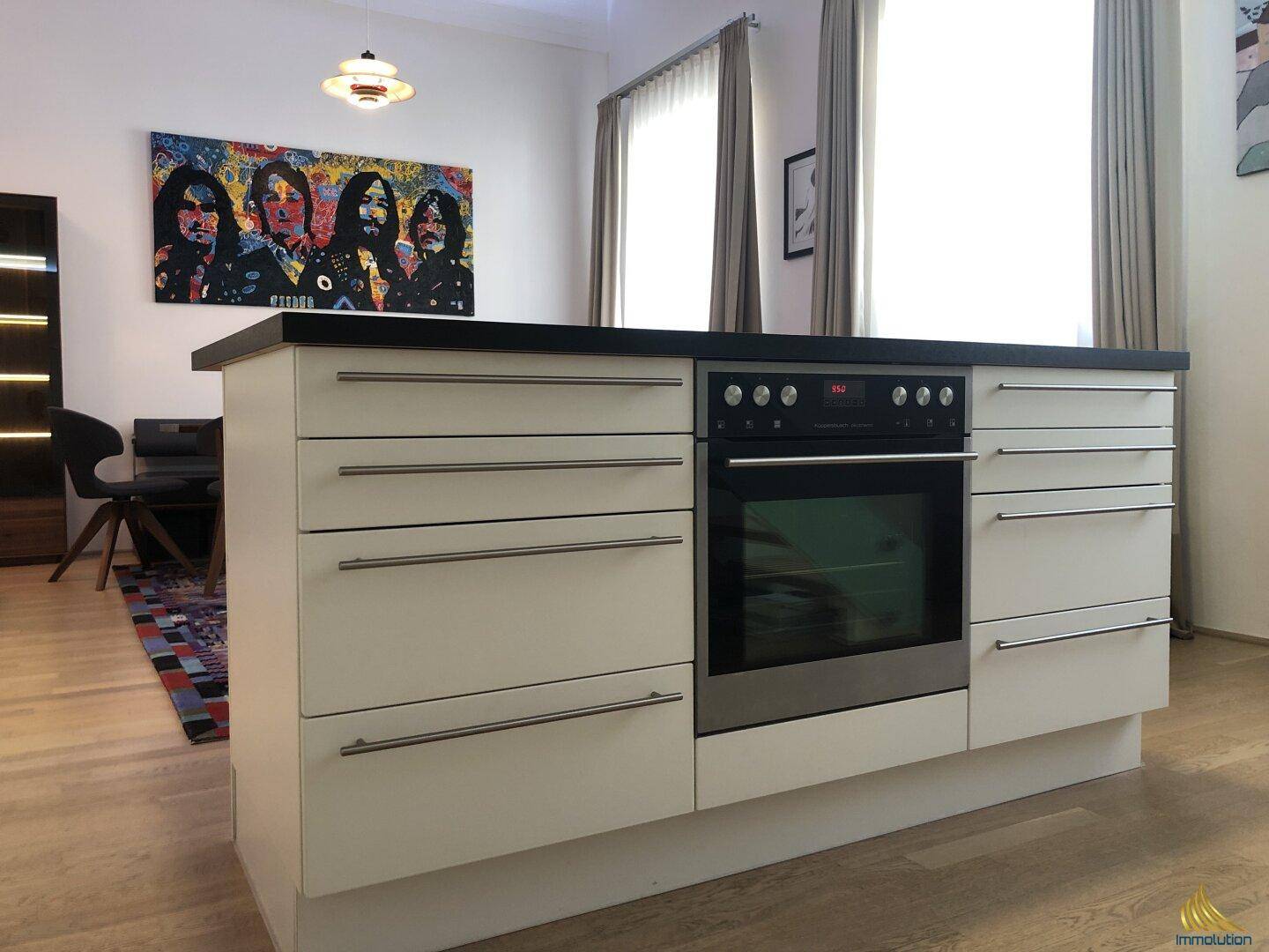 Detailansicht der modernen Kücheninsel mit integriertem Backofen und viel Stauraum.