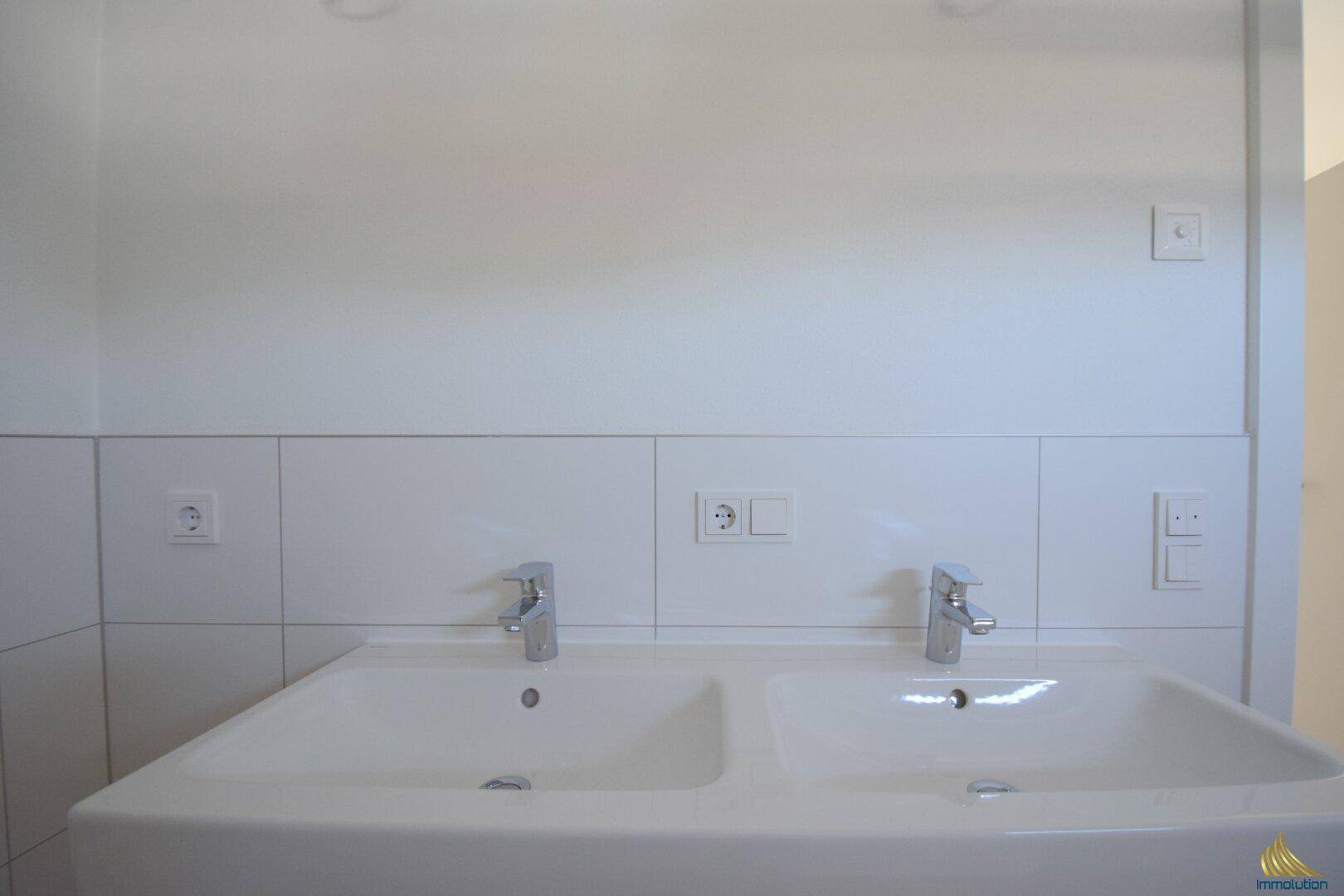 Modernes Badezimmer mit Doppelwaschbecken und weißen Fliesen, bietet viel Komfort.