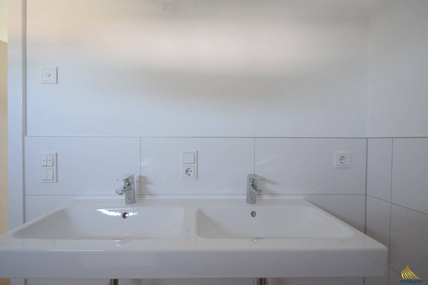 Modernes Badezimmer mit Doppelwaschbecken und weißen Fliesen, bietet Komfort und Funktionalität.