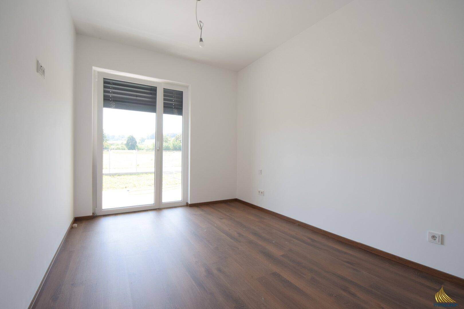 Unmöbliertes Zimmer mit Laminatboden und Fenster mit Rollladen, ideal als Schlaf- oder Arbeitszimmer.