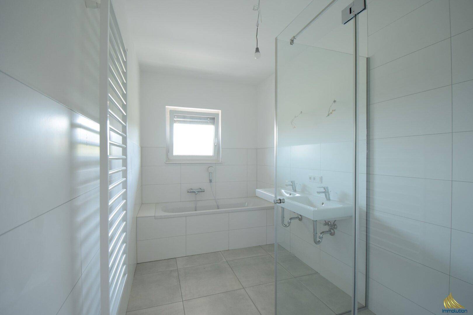 Modernes Badezimmer mit Badewanne, Dusche, Doppelwaschbecken und Fenster.