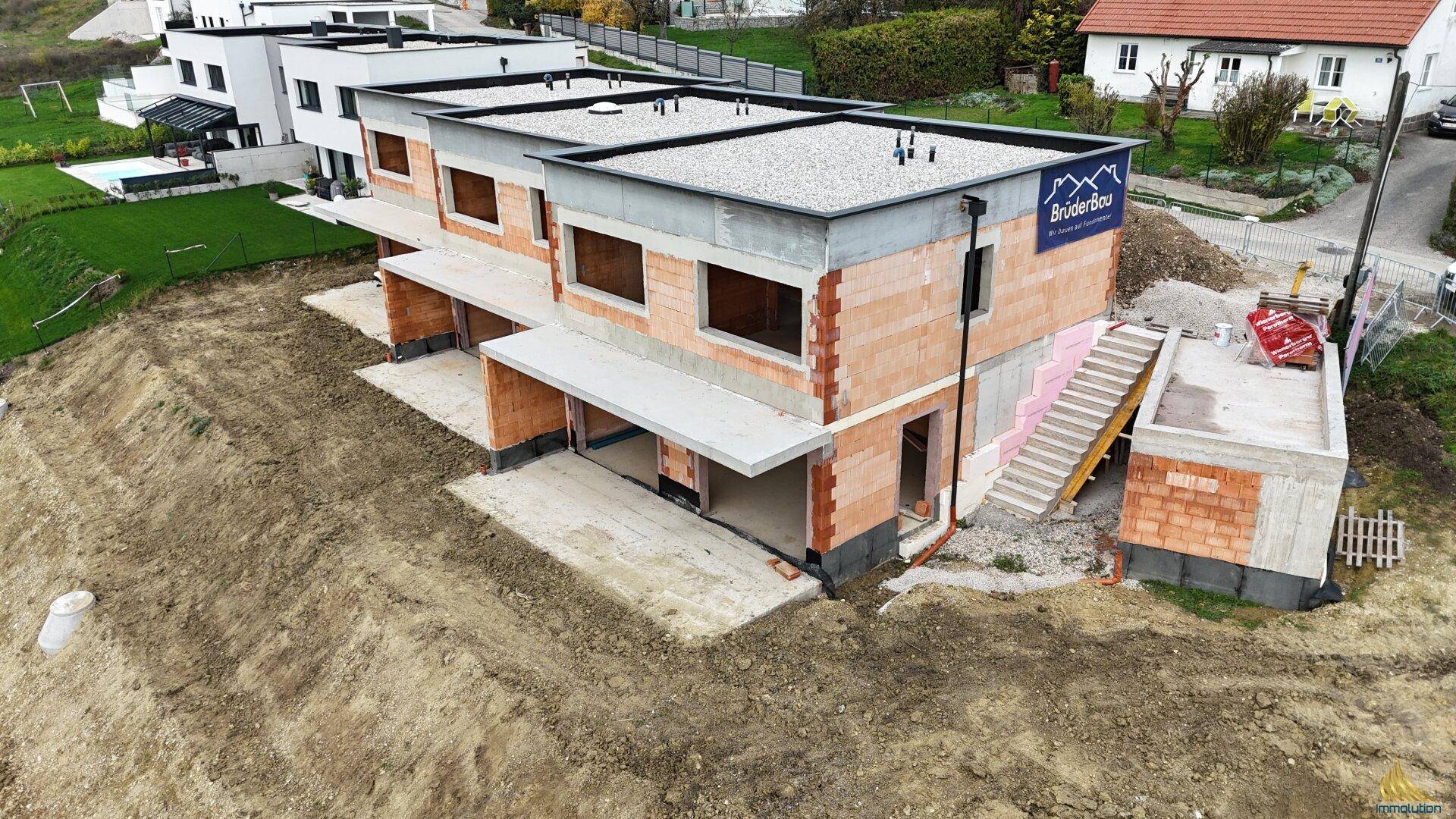 Luftaufnahme der Baustelle mit Reihenhäusern im Rohbau und angrenzendem Treppenaufgang.