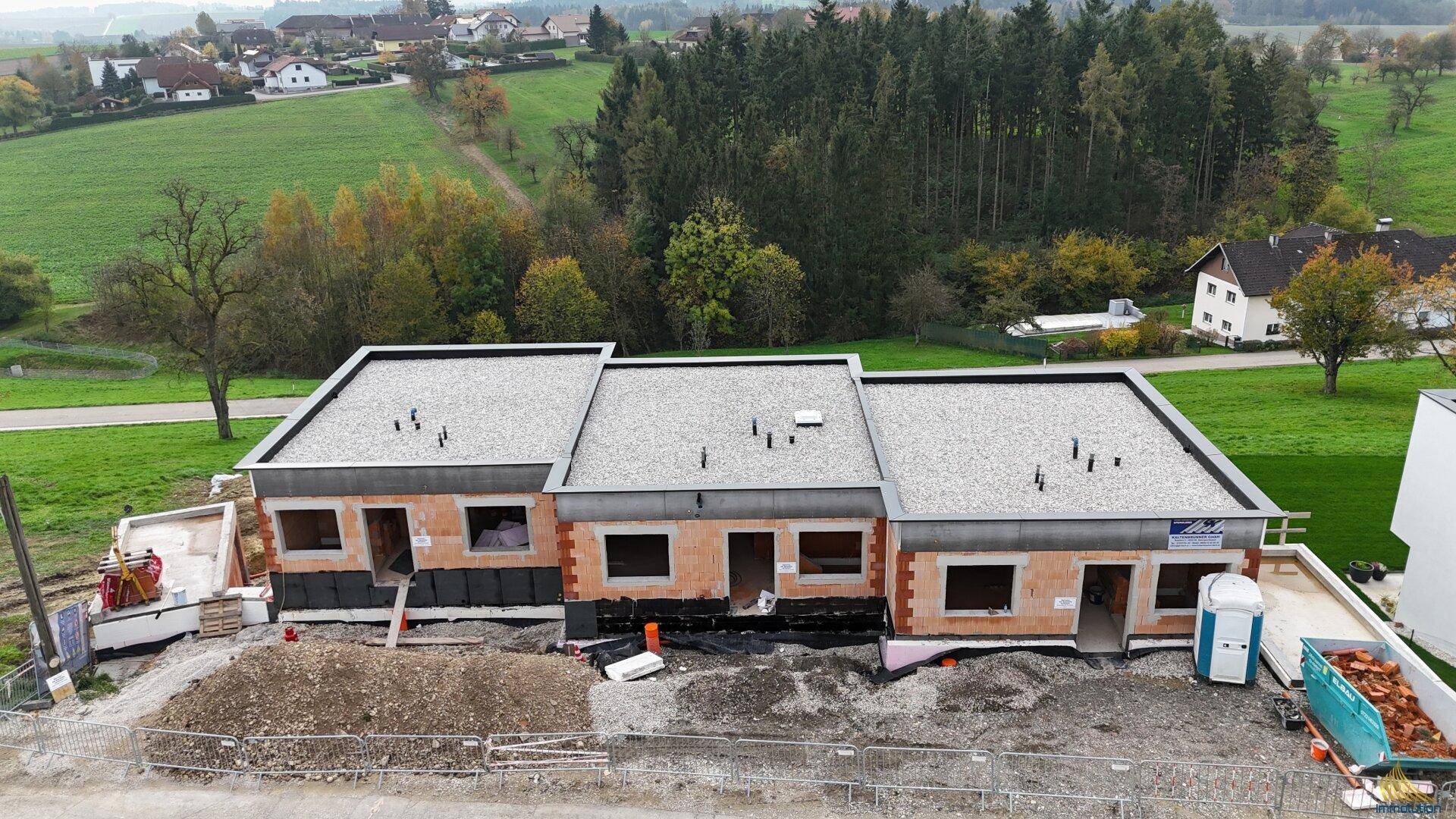 Luftaufnahme der Reihenhäuser im Rohbau mit Blick auf die ländliche Umgebung und Wald.