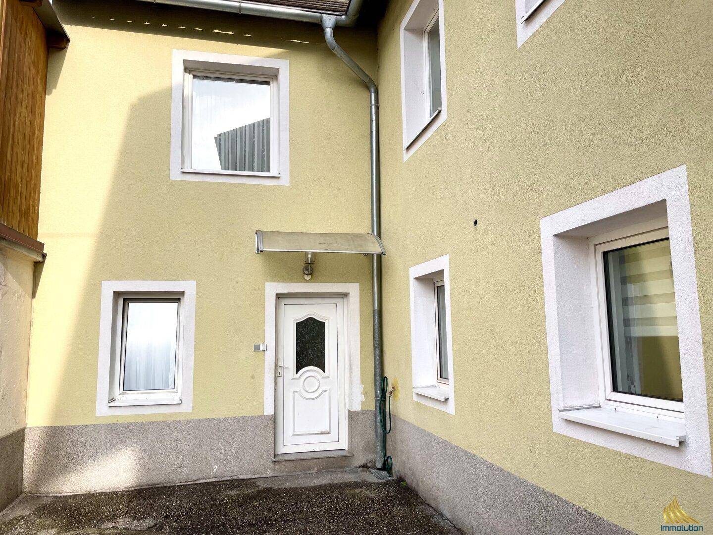 Nahaufnahme der gelben Hausfassade mit Eingangsbereich und Fenstern.