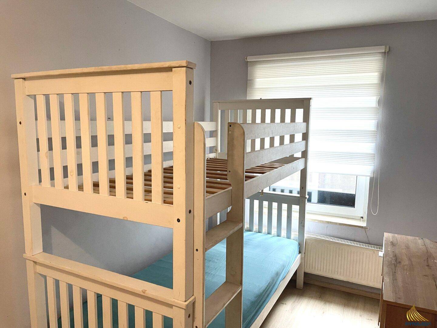 Kinderzimmer mit weißem Etagenbett und Fenster mit Jalousien.