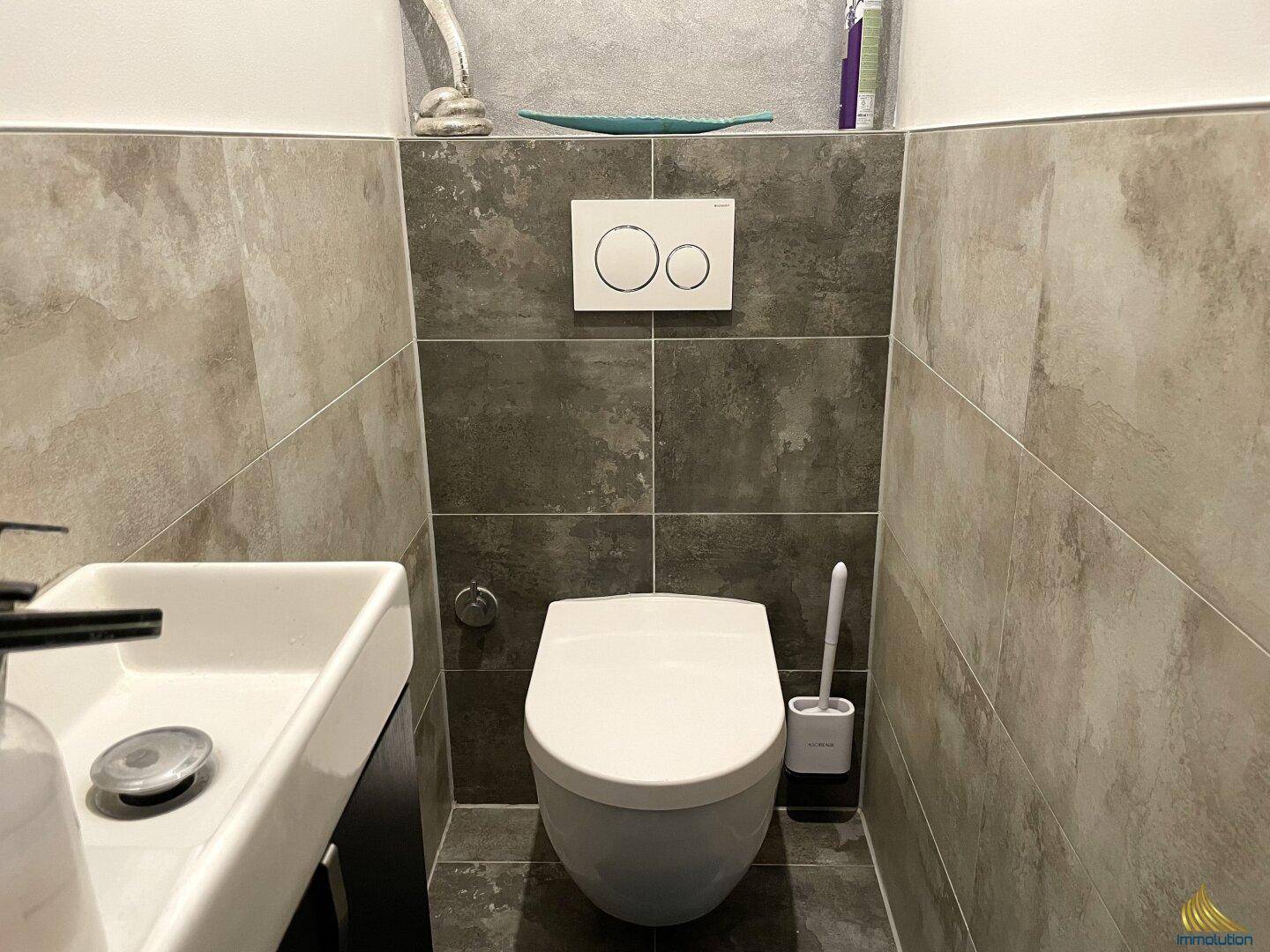 Kleines Gäste-WC mit modernem Wand-WC und Waschbecken, ausgestattet mit dunklen und hellen Fliesen.