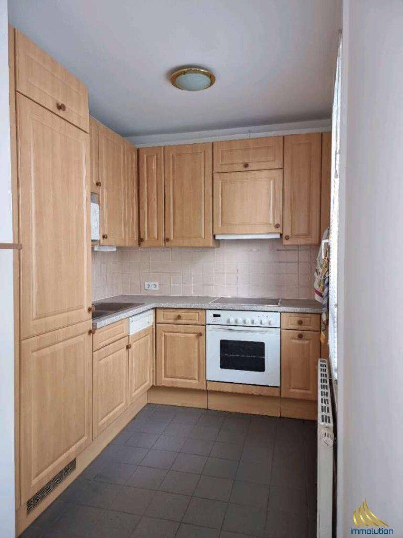 Funktionale Küche mit hellen Holzschränken, Herd, Backofen und integriertem Geschirrspüler.