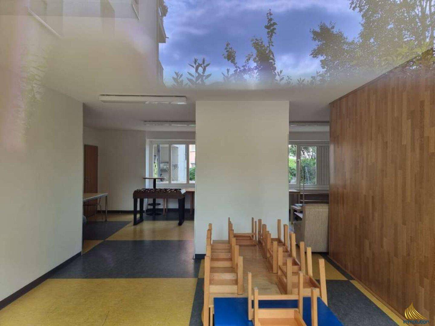 Gemeinschaftsraum mit gelb-schwarzem Fliesenboden, Holzvertäfelung und Kindermöbeln, mit Deckenmalerei.