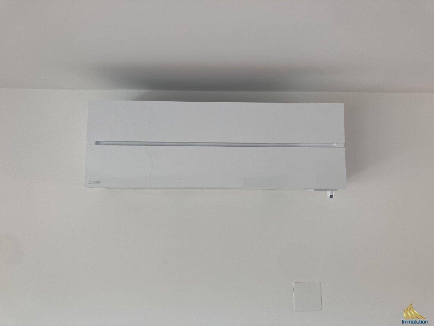 Moderne, weiße Klimaanlage an einer hellen Wand in einem Innenraum des Neubaus.