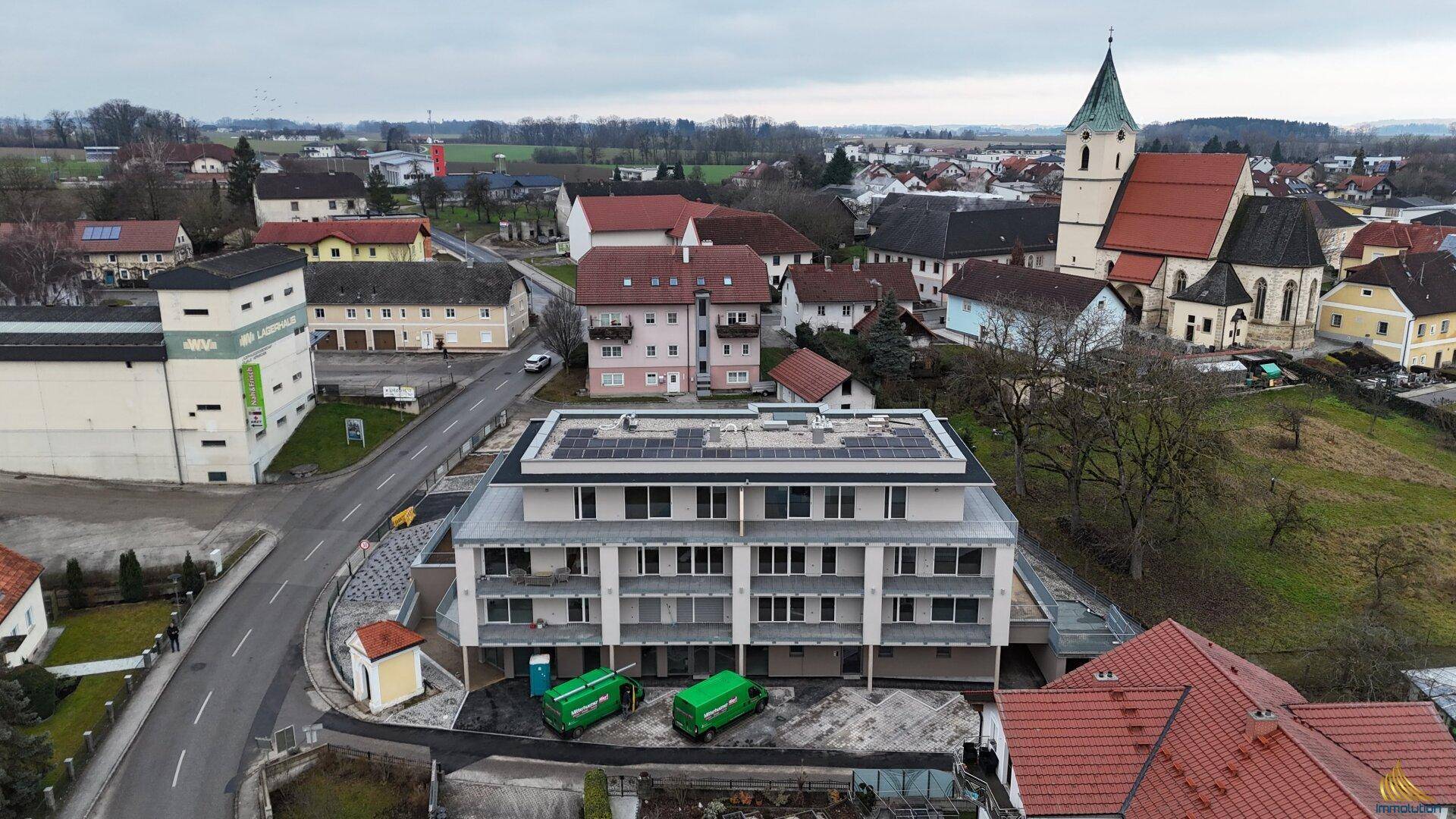 Drohnenansicht eines Neubaus mit Solaranlage auf dem Dach und umliegender ländlicher Bebauung.