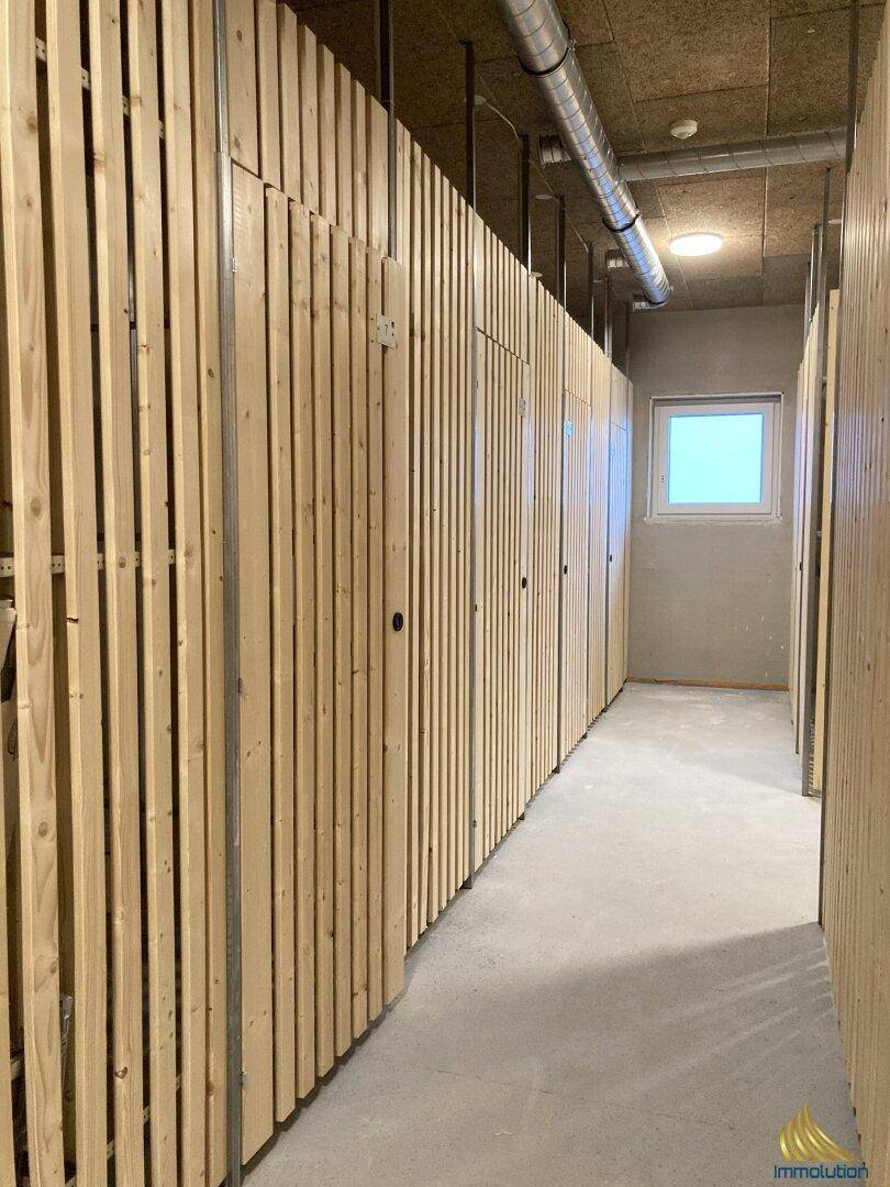 Langer Gang mit individuellen Lagerabteilen aus Holz und einem kleinen Fenster.